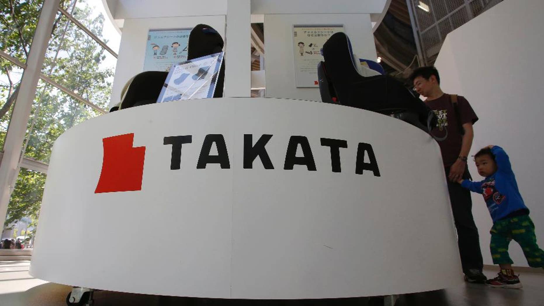 In this Wednesday, May 4, 2016 photo, visitors look at child seats manufactured by Takata Corp. at an automaker's showroom in Tokyo. Takata, the Japanese auto-parts maker behind a massive air-bag recall, is expecting a return to profit for the fiscal year through March 2017, although it just agreed to do more recalls. Tokyo-based Takata reported a 13 billion yen ($120 million) loss Wednesday, May 11, for the fiscal year ended March — the second straight year of red ink. (AP Photo/Shizuo Kambayashi)