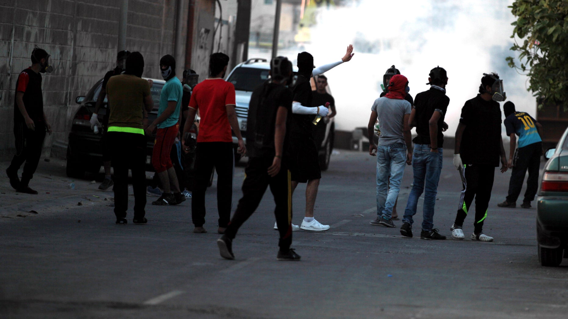 Bahraini youths carrying petrol bombs and stones confront riot police firing tear gas, stun grenades and shotguns after the funeral for Hussain Mahdi Habib, 20, in Sitra, Bahrain, on Sunday, Oct. 20, 2013. Habib, who was wanted by authorities for escaping from prison, received a 15-year sentence in absentia for his participation in the pro-democracy uprising, and was found beaten and shot dead. (AP Photo/Hasan Jamali)