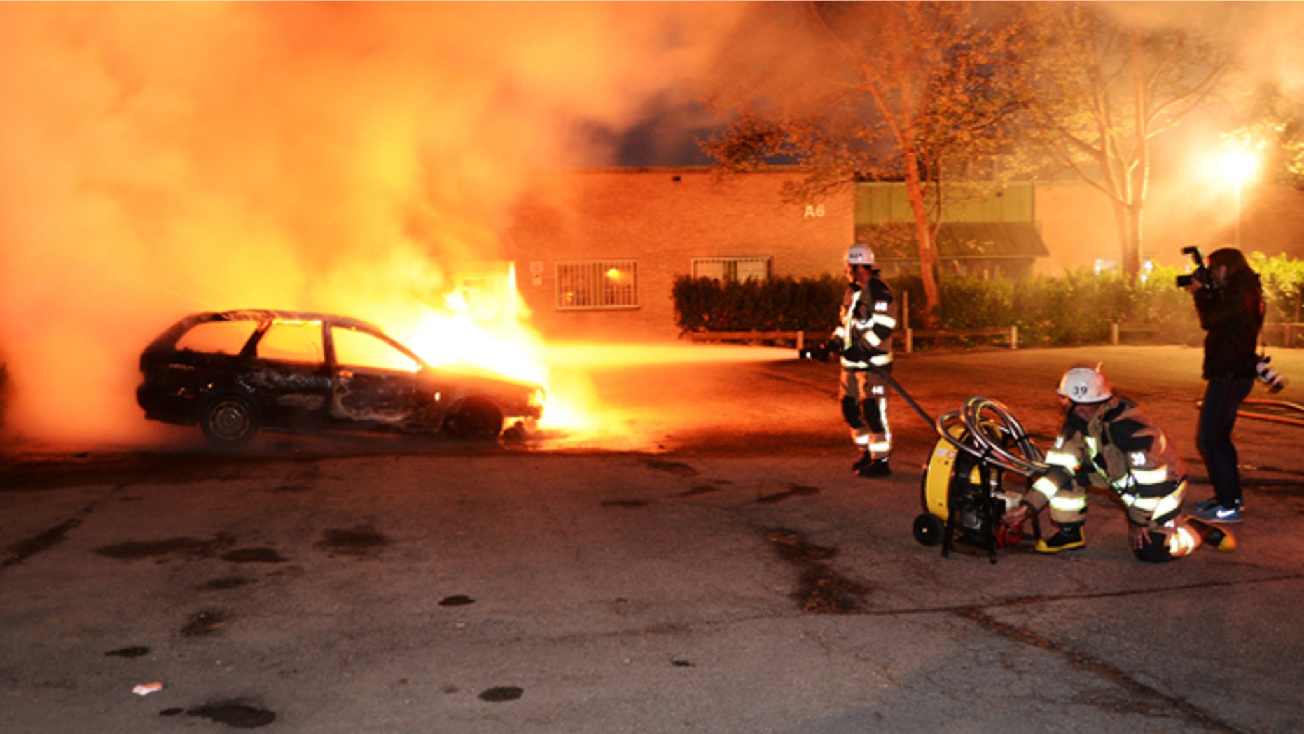 May 21, 2013: Firemen extinguish a burning car in the Stockholm suburb of Kista after youths rioted in several different suburbs around Stockholm for a third consecutive night.
