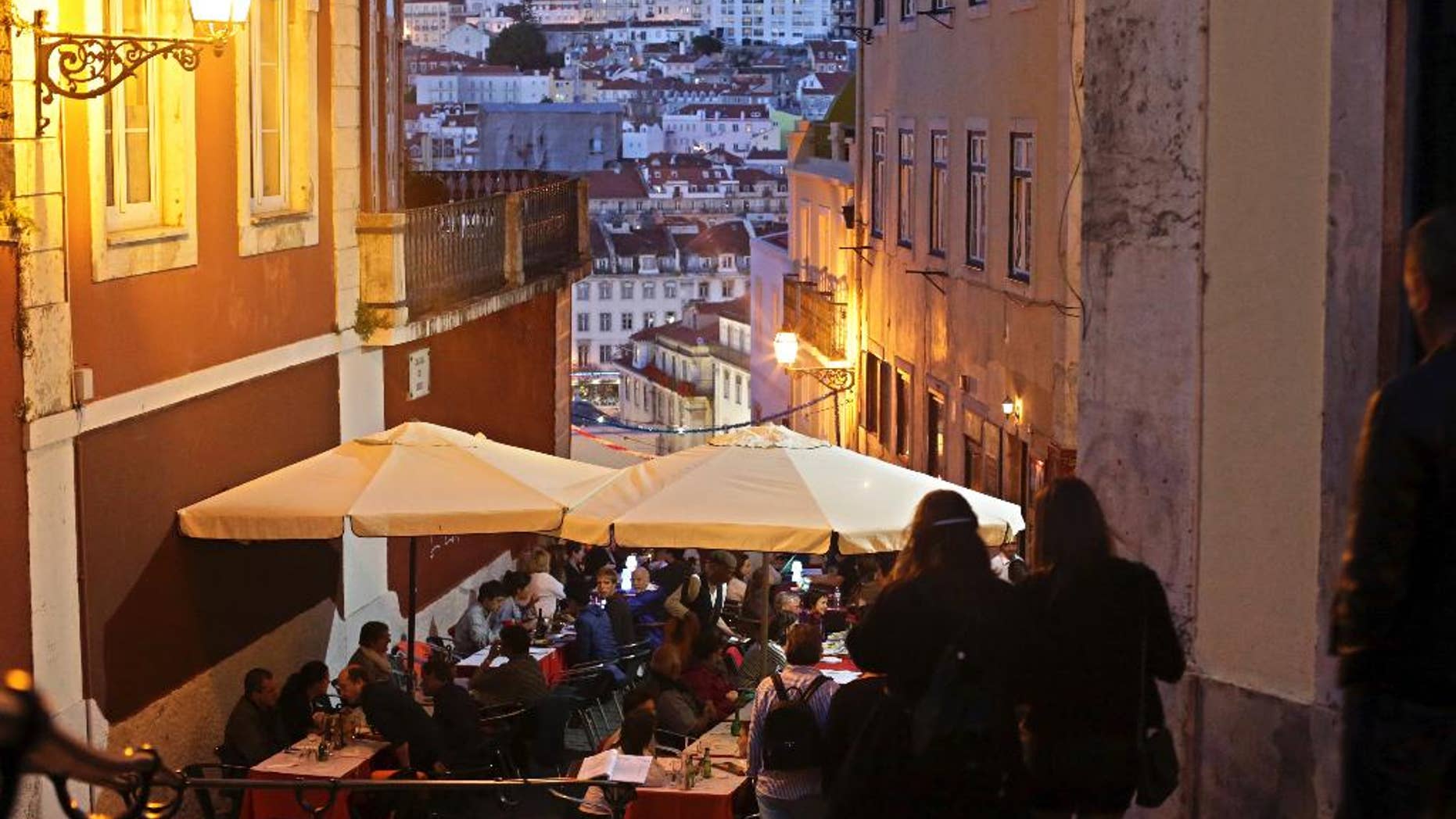 FILE - In this May 25, 2016 file photo, tourists have dinner at restaurant tables set outside with a view of Saint George castle in the background, in Lisbon. Portugal's fragile economy is getting a tonic from tourism this year, with revenue up by more than 10 percent through October including a 20 percent jump in visitors from the United States. Tourism minister Ana Mendes Godinho says the sector brought in some 11 billion euros ($11.5 billion) in the first 10 months of 2016 — about 1 billion euros more than the same period last year. (AP Photo/Armando Franca)