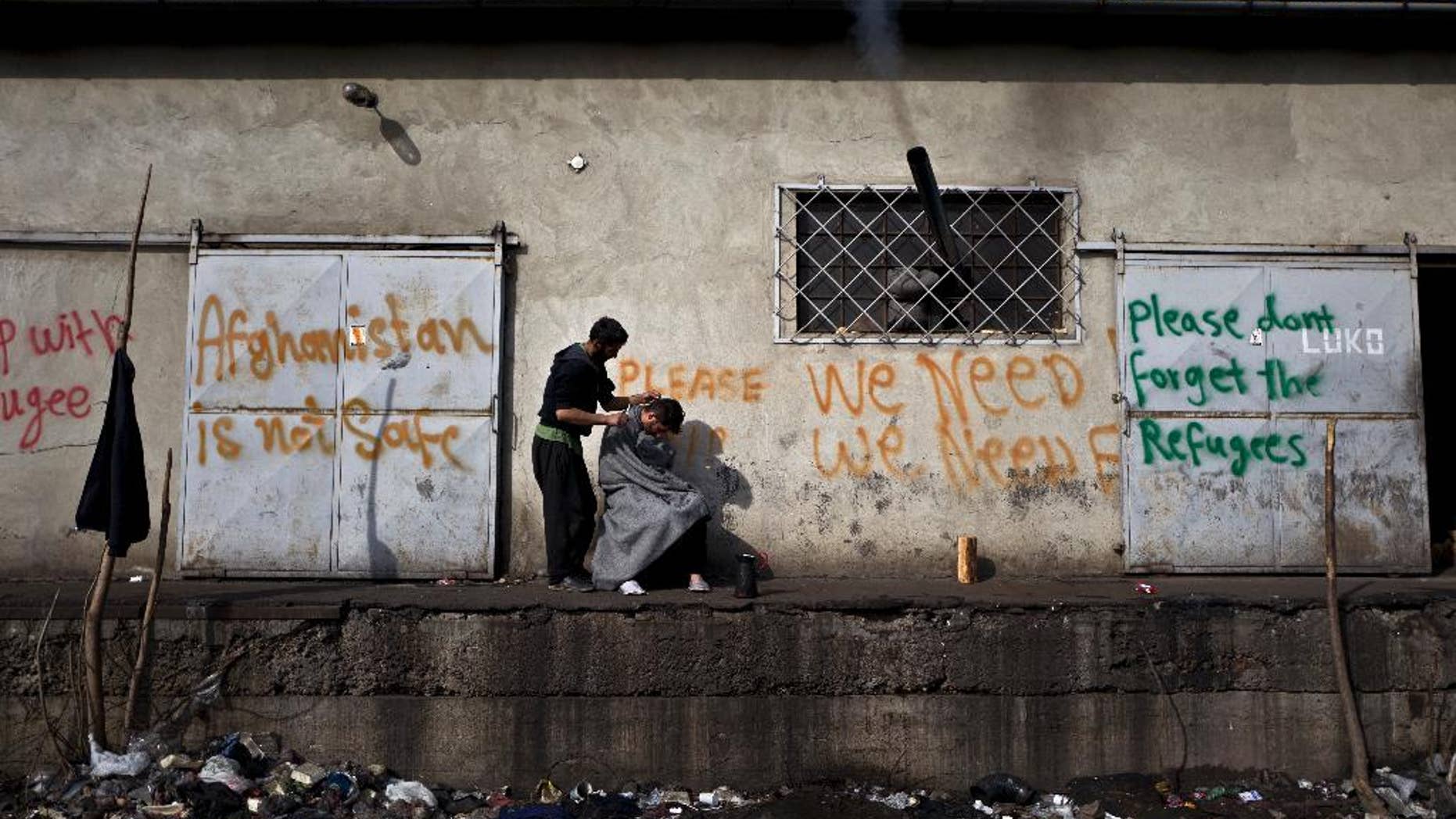 An Afghan refugee man gives a haircut to a friend in an abandoned warehouse where they have taken refuge in Belgrade, Serbia, Wednesday, Feb. 22, 2017. Hundreds of migrants have been sleeping rough in freezing conditions in central Belgrade looking for ways to cross the heavily guarded EU borders. (AP Photo/Muhammed Muheisen)