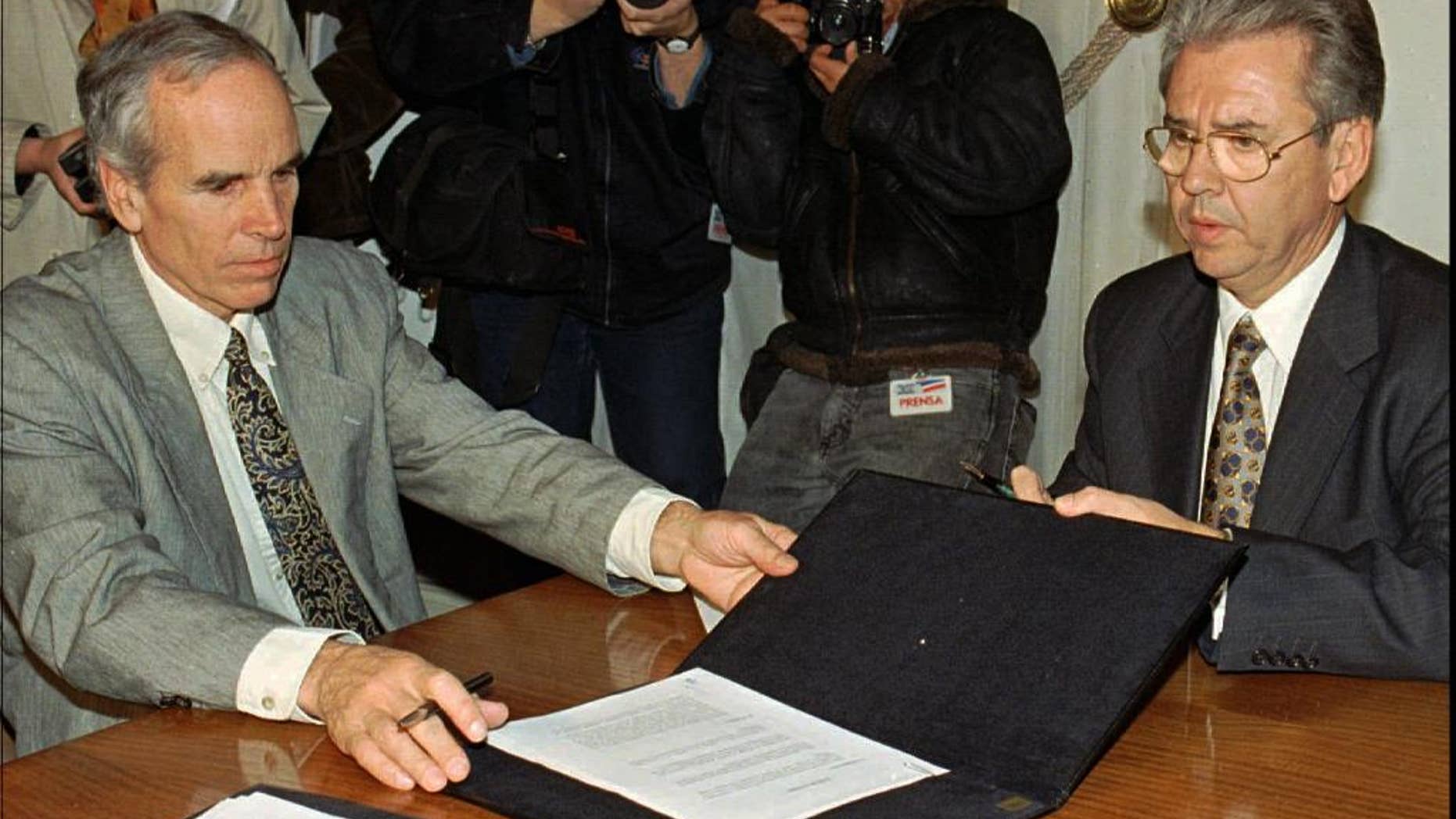 FILE - In this July 7, 1997, file photo, American millionaire Douglas Tompkins, left, and Juan Villarzu, chief of staff of the Chilean president, hold the text of an accord signed in Santiago, Chile. Officials in Chile said Tuesday, Dec. 8, 2015, that the wealthy U.S. businessman and environmental activist has died from severe hypothermia in a kayaking accident. (AP Photo/Santiago Llanquin, File)
