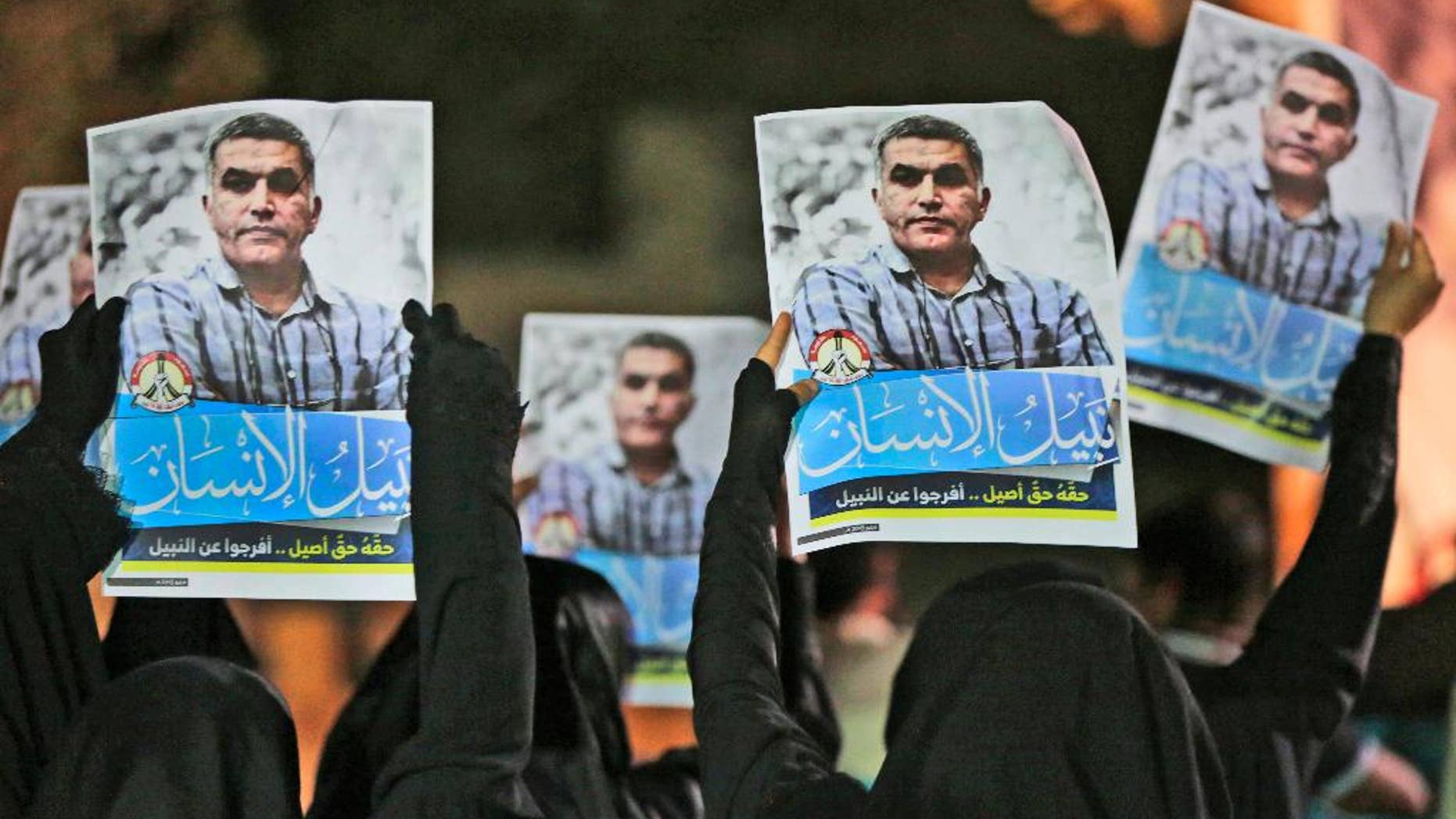 FILE- In this Thursday, May 14, 2015 file photo, Bahraini anti-government protesters hold up images of jailed human rights activist Nabeel Rajab during a solidarity protest outside his home in Bani Jamra, Bahrain. A jailed activist in Bahrain on trial for allegedly spreading "false news" is being investigated over a letter published in his name by French newspaper. Bahrain's Interior Ministry issued a statement early Thursday, Dec. 22, 2016, announcing the new probe focusing on Nabeel Rajab over the article published by Le Monde on Tuesday. (AP Photo/Hasan Jamali, File)