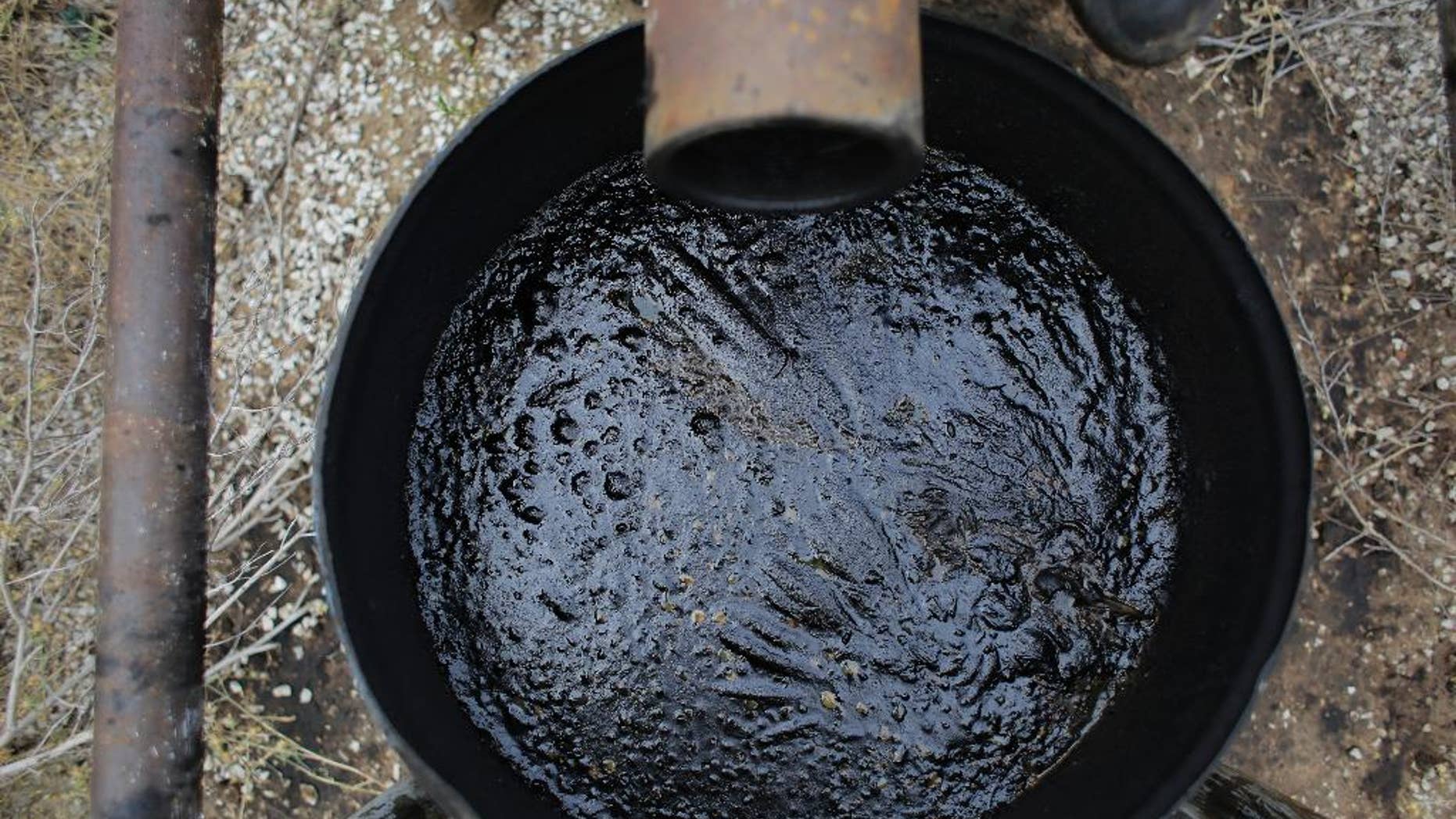 In this Friday, May 13, 2016, photo, an overflow barrel holds oil near a storage tank on a South Texas ranch near Bigfoot, Texas. The agencies that regulate the oil and gas industry are running out of money just as some problems in the oilfields are worsening. Meanwhile, defunct companies are abandoning wells that are in danger of deteriorating. (AP Photo/Eric Gay)