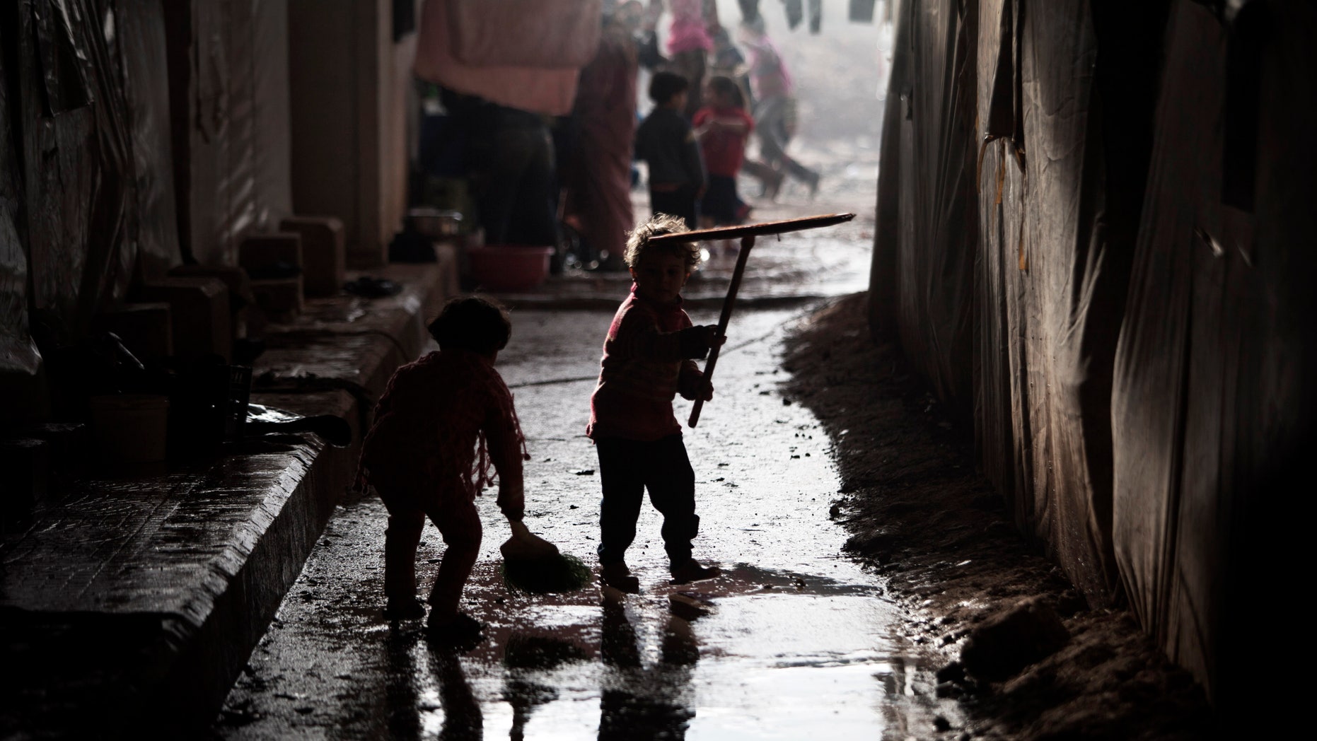 Displaced Syrian children play with cleaning tools in the Azaz camp for displaced people, north of Aleppo province, Syria, Thursday, Feb. 21, 2013. According to Syrian activists the number of people in the Azaz camp has grown by 3,000 in the last weeks due to heavier shelling by government forces. (AP Photo/Manu Brabo)