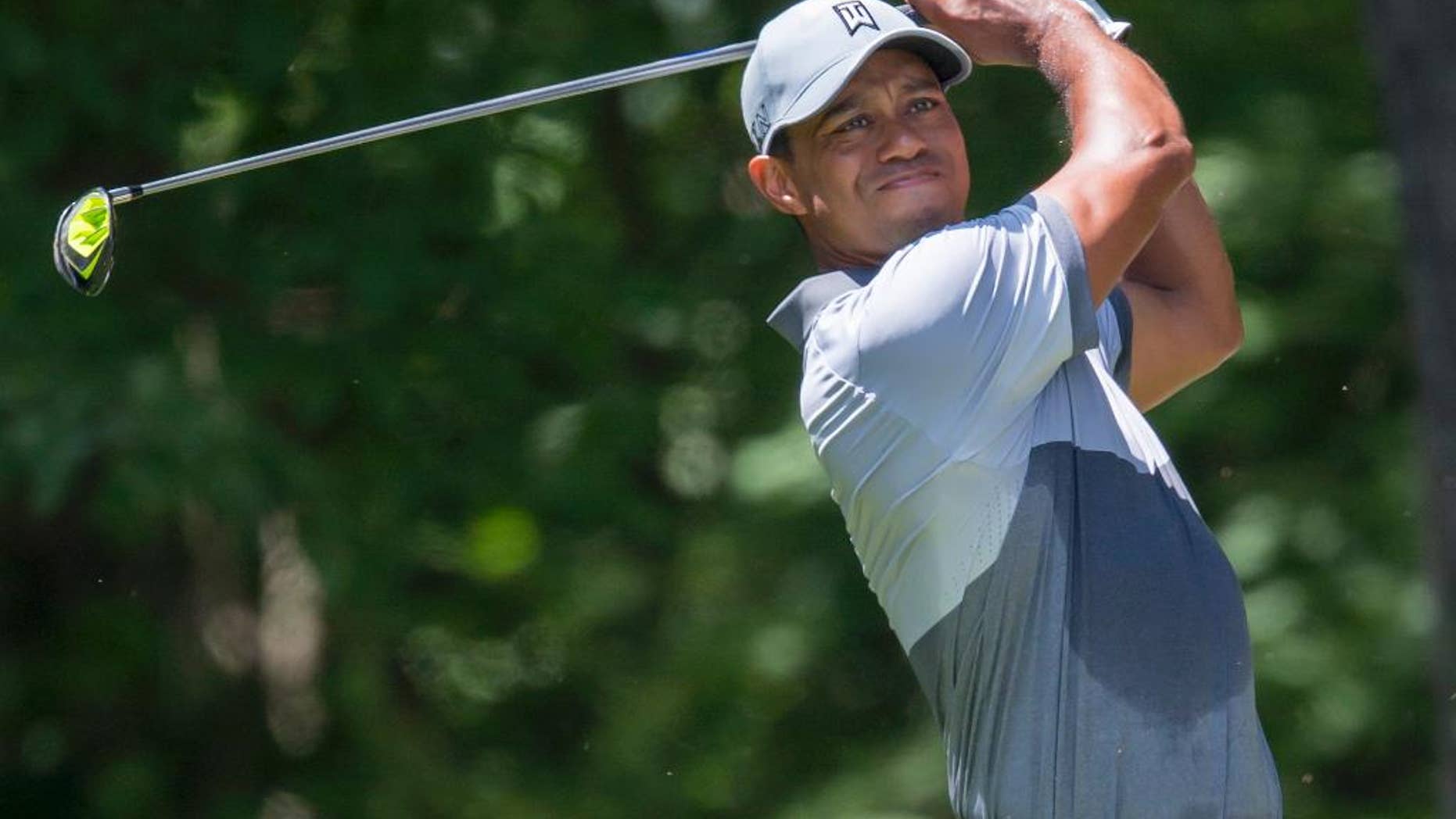 FILE - In this Saturday, Aug. 22, 2015 file photo, Tiger Woods tees off on the second hole during the third round of the Wyndham Championship golf tournament at Sedgefield Country Club in Greensboro, N.C. The azaleas are blooming, the pollen is swirling, and green sport coats are about to be in vogue for one whole week. Yet something is missing at this dawning of spring. Tiger Woods.(AP Photo/Rob Brown, File)