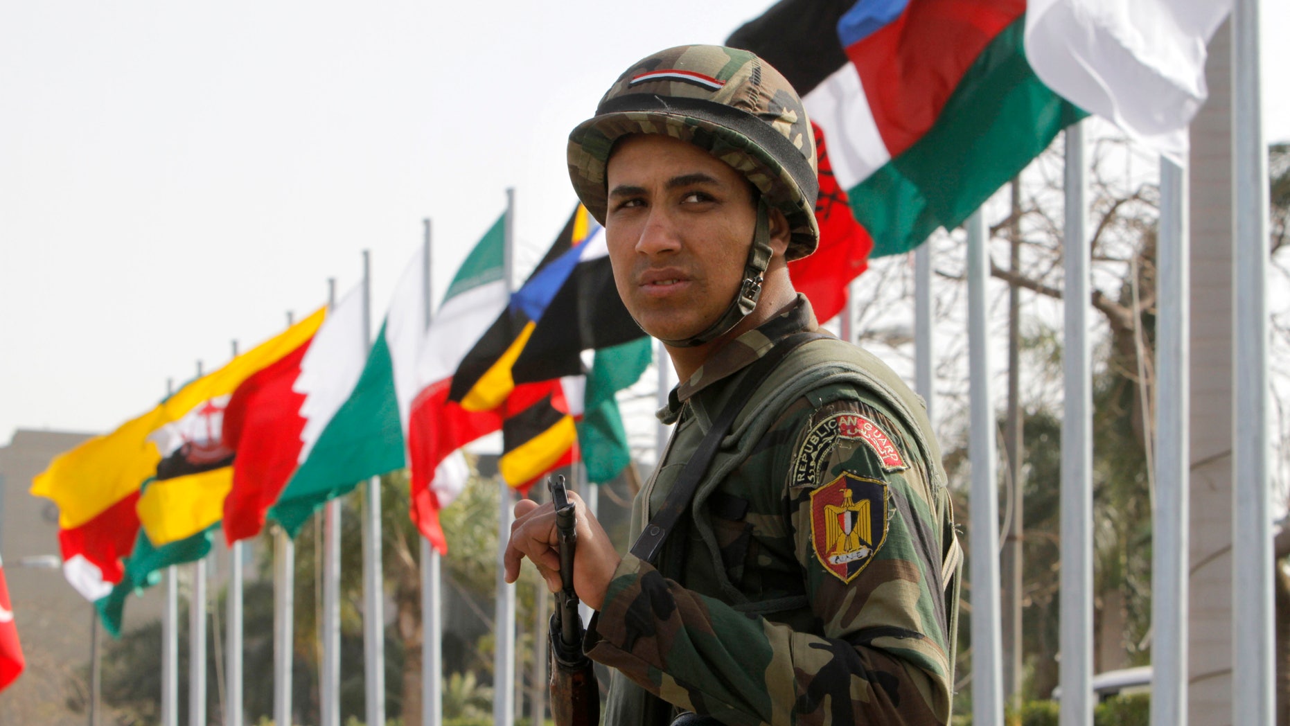 An Egyptian presidential guard soldier stands in front of flags of participating countries at the 12th summit of the Organization of Islamic Cooperation in Cairo, Egypt, Wednesday, Feb. 6, 2013. The summit aims to address a wide range of issues including, Palestinian statehood, the Syrian crisis, poverty in the Islamic world and conflicts in Afghanistan and Somalia. (AP Photo/Amr Nabil)