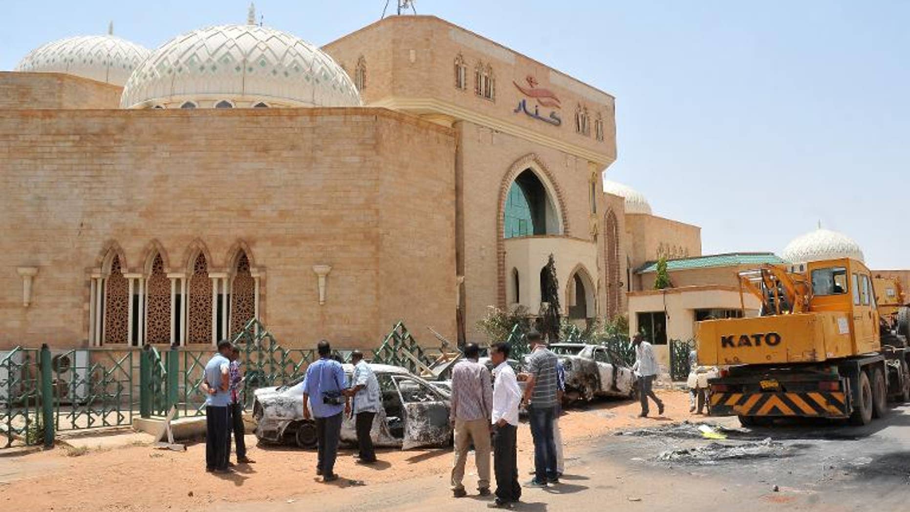 People look at burnt vehicles on September 26, 2013 in the Sudanese capital Khartoum after rioting erupted following a decision by the government to scrap fuel subsidies