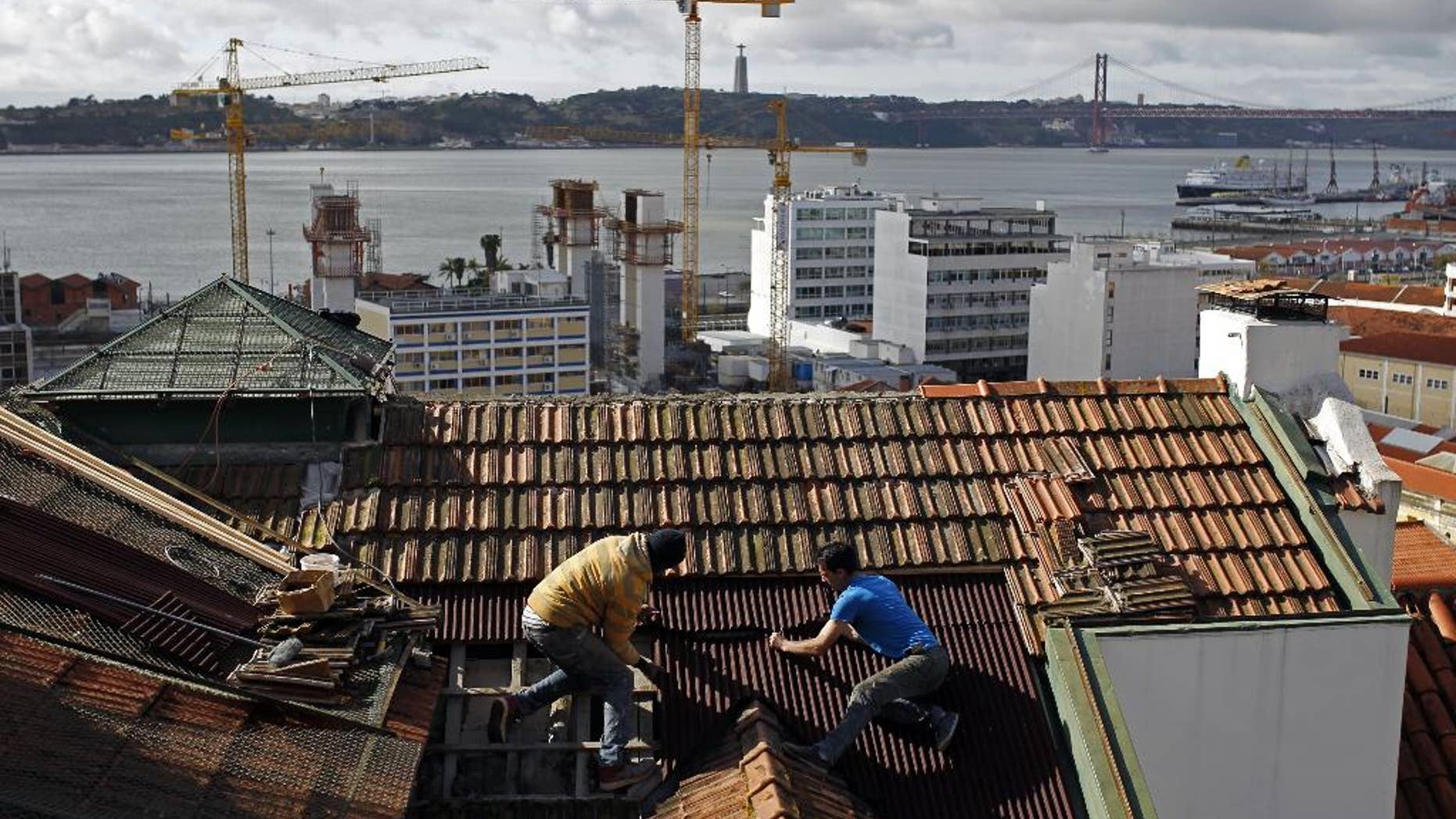 FILE - In this Feb. 28, 2014 file photo, construction workers repair the roof of a building in Lisbon. The country’s construction sector collapsed amid the financial crisis, which saw the state take a 78 billion-euro ($87 billion) bailout in 2011. The number of construction workers has more than halved from 612,000 in 2005 to roughly 277,000. (AP Photo/Francisco Seco)