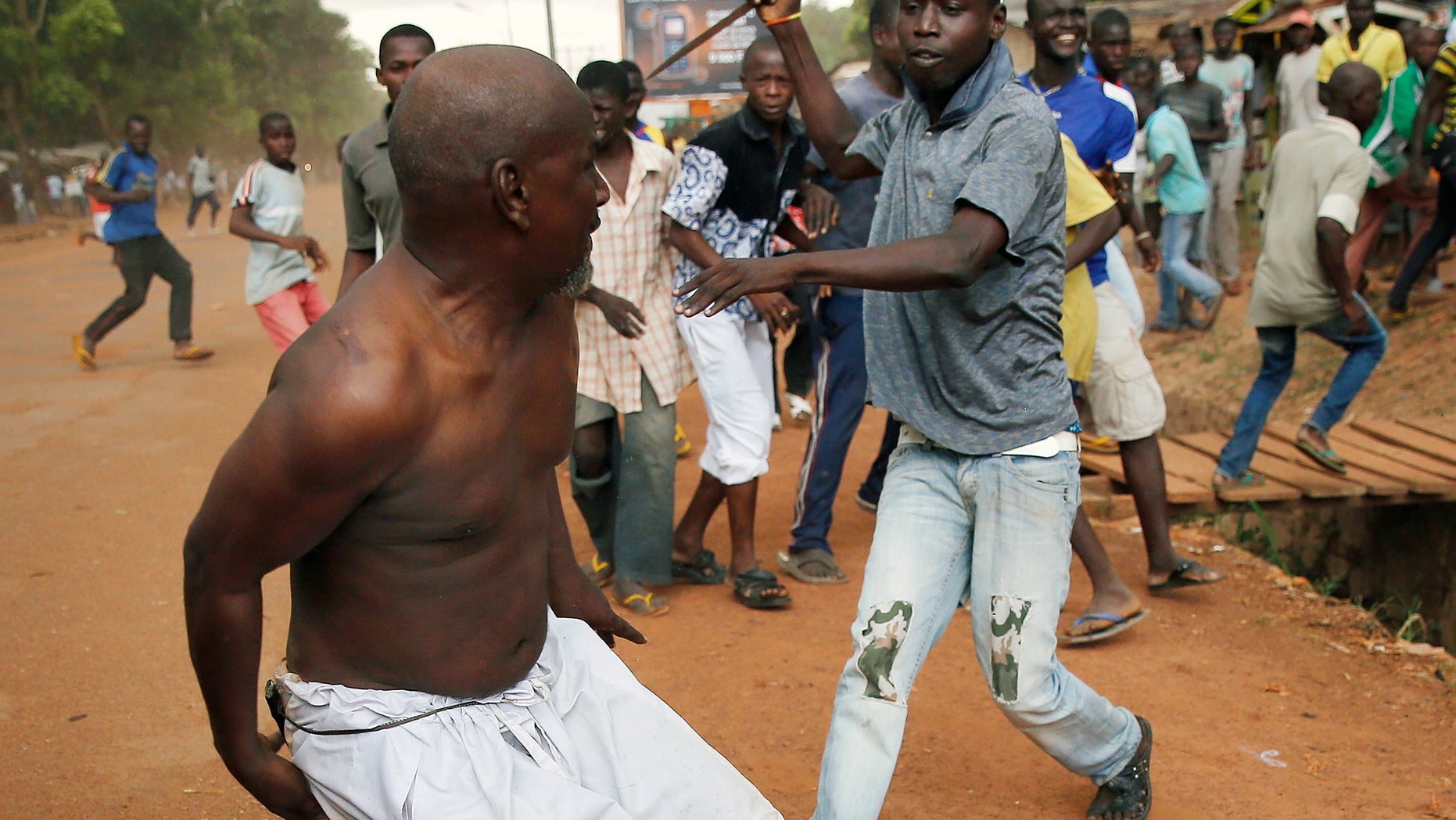 A Christian man chases a suspected Seleka officer in civilian clothes with a knife near the airport in Bangui, Central African Republic, Monday Dec. 9, 2013. Both Christian and Muslim mobs went on lynching sprees as French Forces deployed in the capital. The Seleka man was taken into custody by French forces who fired warning shots to disperse the crowds. (AP Photo/Jerome Delay)