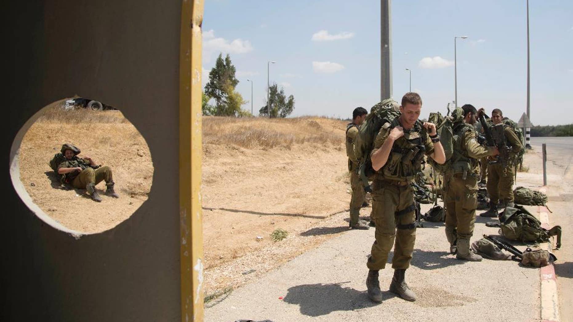 FILE- In this Aug. 27, 2014 file photo, Israeli soldiers rest in a bus satiation near the southern Israeli town of Sderot, next to the Israeli Gaza border. Breaking the Silence, an organization of former Israeli soldiers dedicated to shedding light on the dark side of the military is coming increasingly under fire, roiling a country in the grips of a battle against the burgeoning threat of international isolation and boycotts. The group, says that without its work, stories of improper or even illegal behavior against Palestinians would remain hidden from an Israeli public that reveres the military. (AP Photo/Oded Balilty, File)