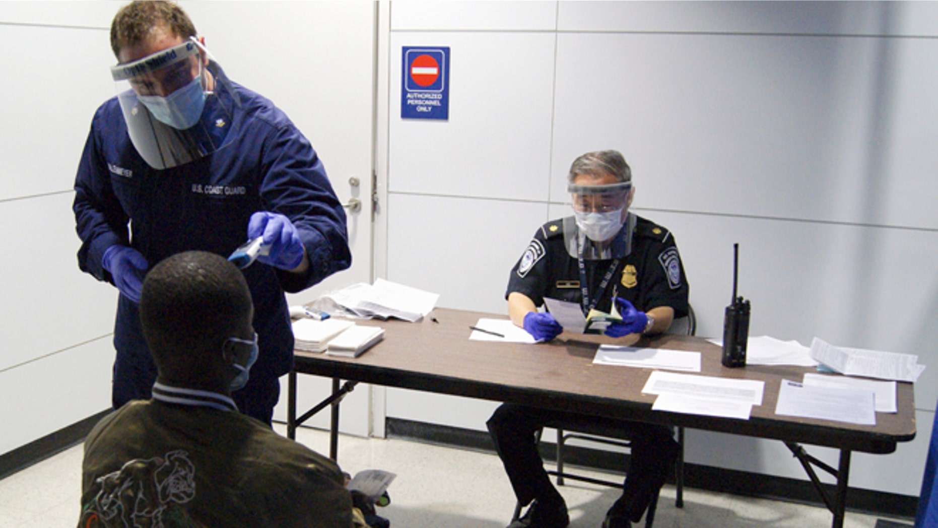 FILE- In this Thursday, Oct. 16, 2014, file photo released by U.S. Customs and Border Protection, U.S. Coast Guard Health Technician Nathan Wallenmeyer, left, and CBP supervisor Sam Ko, right, conduct prescreening measures on a passenger who has arrived from Sierra Leone at O'Hare International Airport's Terminal 5 in Chicago. Demands are rising in Washington for the U.S. to ban travelers from countries in West Africa, but the Obama administration is resisting and says the screening measures already in place for travelers are more effective. (AP Photo/U.S. Customs and Border Protection, Melissa Maraj, File)