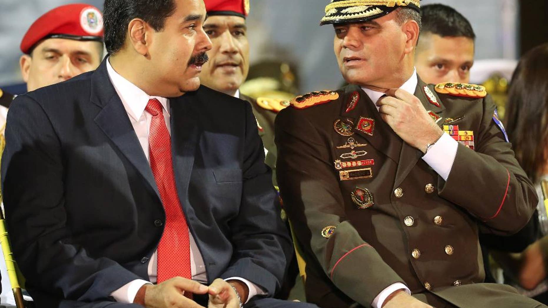 FILE - In this Oct. 27, 2014 file photo, Venezuela's President Nicolas Maduro, left, speaks with his Defense Minister Gen. Vladimir Padrino, during the new military chief's swearing-in ceremony at the Fort Tiuna military base in Caracas, Venezuela. Maduro on Monday, July 11, 2016 said he was creating a new government initiative to boost production and guarantee the smooth distribution of food supplies. He says that what is called the Great Mission of Sovereign Supplying will be headed Padrino, who will coordinate the work of every ministry. (AP Photo/Ariana Cubillos, File)