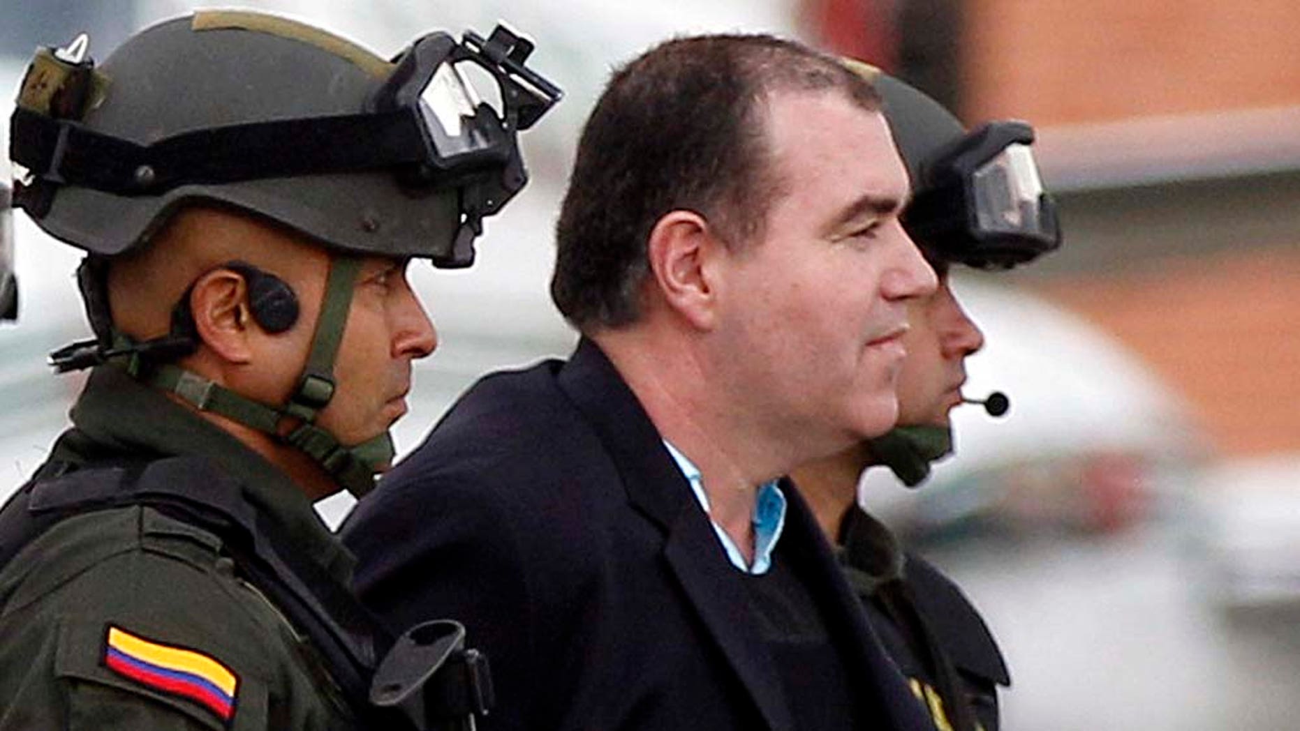 Colombian police officers escort alleged drug trafficker Walid âThe Turkâ Makled to a waiting plane at the military airport in Bogota, Colombia, Monday May 9, 2011. The Venezuelan citizen of Syrian descent was arrested late last year on a U.S. warrant in Colombia. Colombia President Juan Manuel Santos said the law favored Makled being sent to Venezuela instead of the U.S. because it was the first country to request his extradition.(AP Photo/Fernando Vergara)
