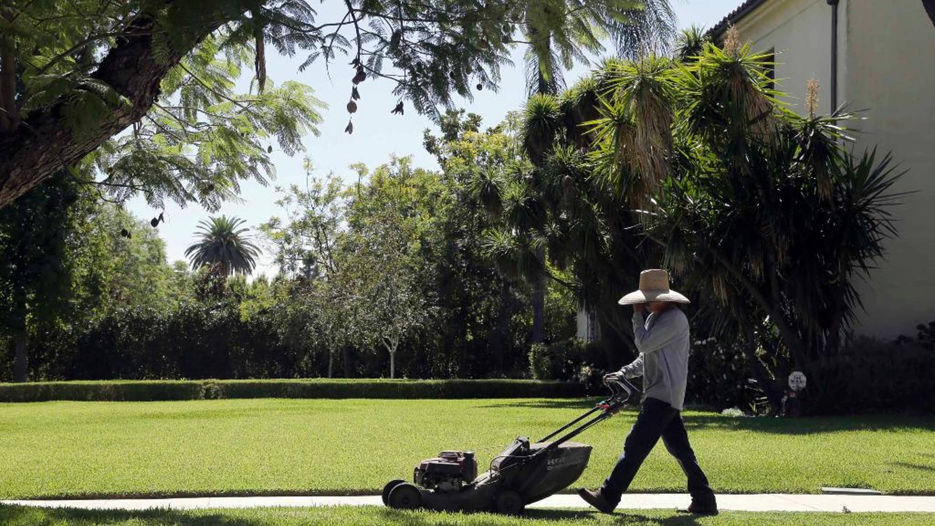 File - In this Oct. 1, 2015 file photo, a gardener mows a lawn in Pasadena, Calif. State officials say residents of drought-weary California in November missed their 25 percent water conservation mandate for a second month running. The chair of the State Water Resources Control Board, says California remains on course to beat its long-term goal through February. (AP Photo/Nick Ut, File)