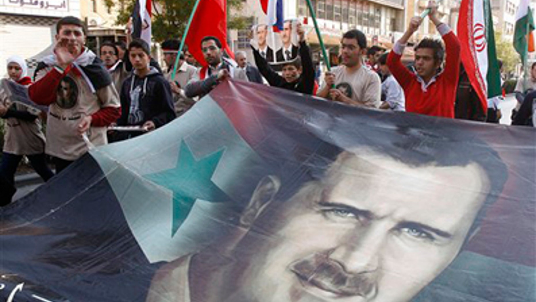 Nov. 25, 2011: Pro-Syrian regime protesters shout slogans and carry a huge portrait of the Syrian president Bashar Assad during a protest against the Arab League decisions, in Damascus, Syria.