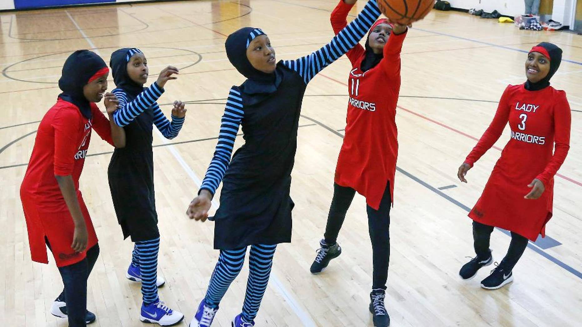 FILE - In this June 16, 2015, file photo, East African Muslim girls practice basketball in their new uniforms in Minneapolis. Members of basketball's international governing body are expected to vote to eliminate a rule that bans religious headgear during competition. The vote could come during a meeting on Thursday or Friday, May 5, 2017. Headgear was banned for safety reasons two decades ago out of fear it could fall off, causing a player to slip or become entangled. (AP Photo/Jim Mone, File)