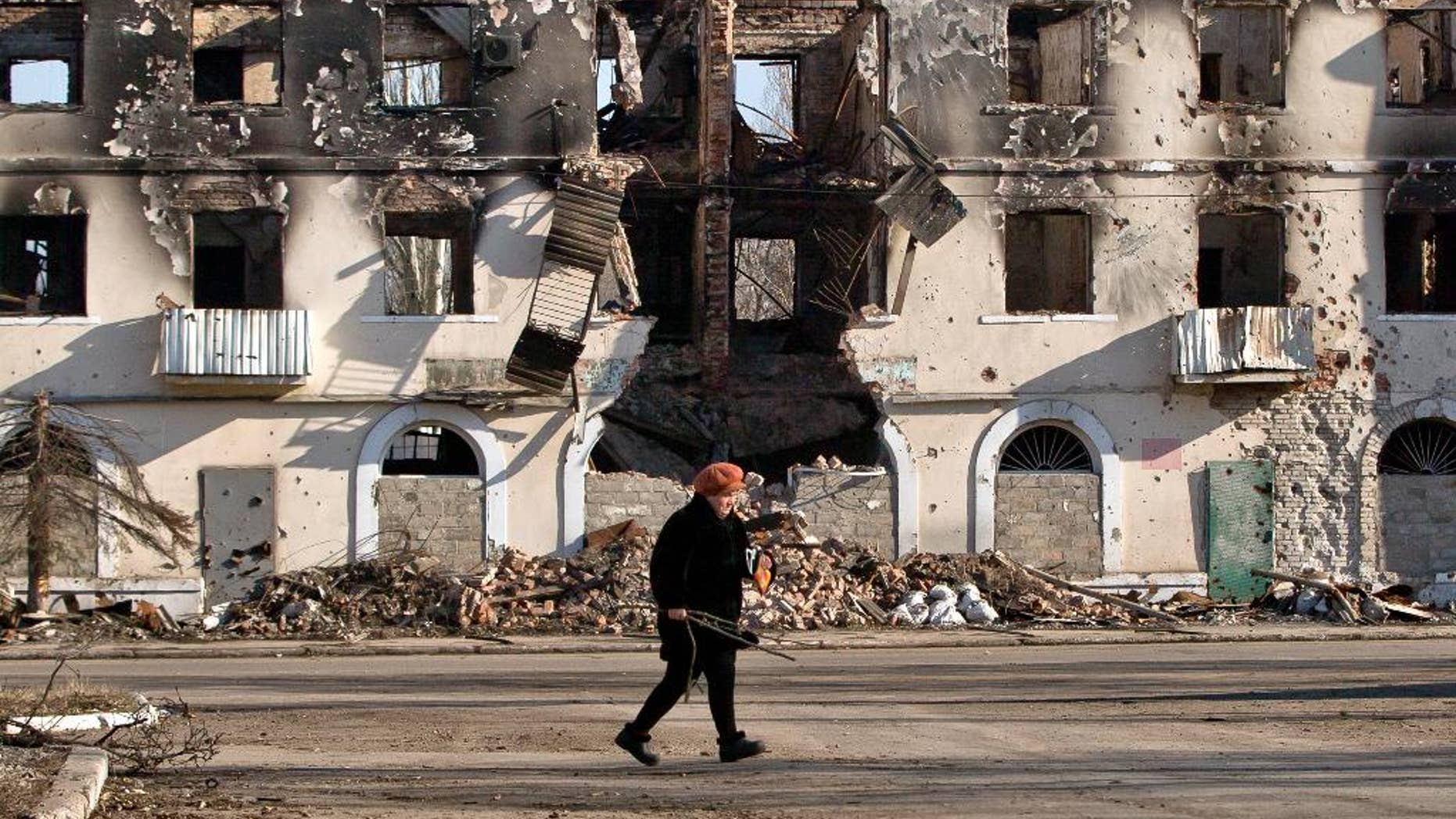 March 9, 2015: An elderly woman walks by a destroyed building in Vuhlehirsk, Ukraine.