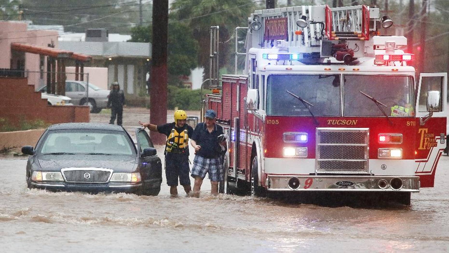 Tucson firefighters with Ladder 9 attend to a stranded motorist as heavy rains flood the intersection of North Country Club Road and East Seneca Street, Tuesday, Aug. 9, 2016, in Tucson, Ariz. Heavy rain associated with Tropical Storm Javier in Mexico fell over the American Southwest. (Mike Christy/Arizona Daily Star via AP)