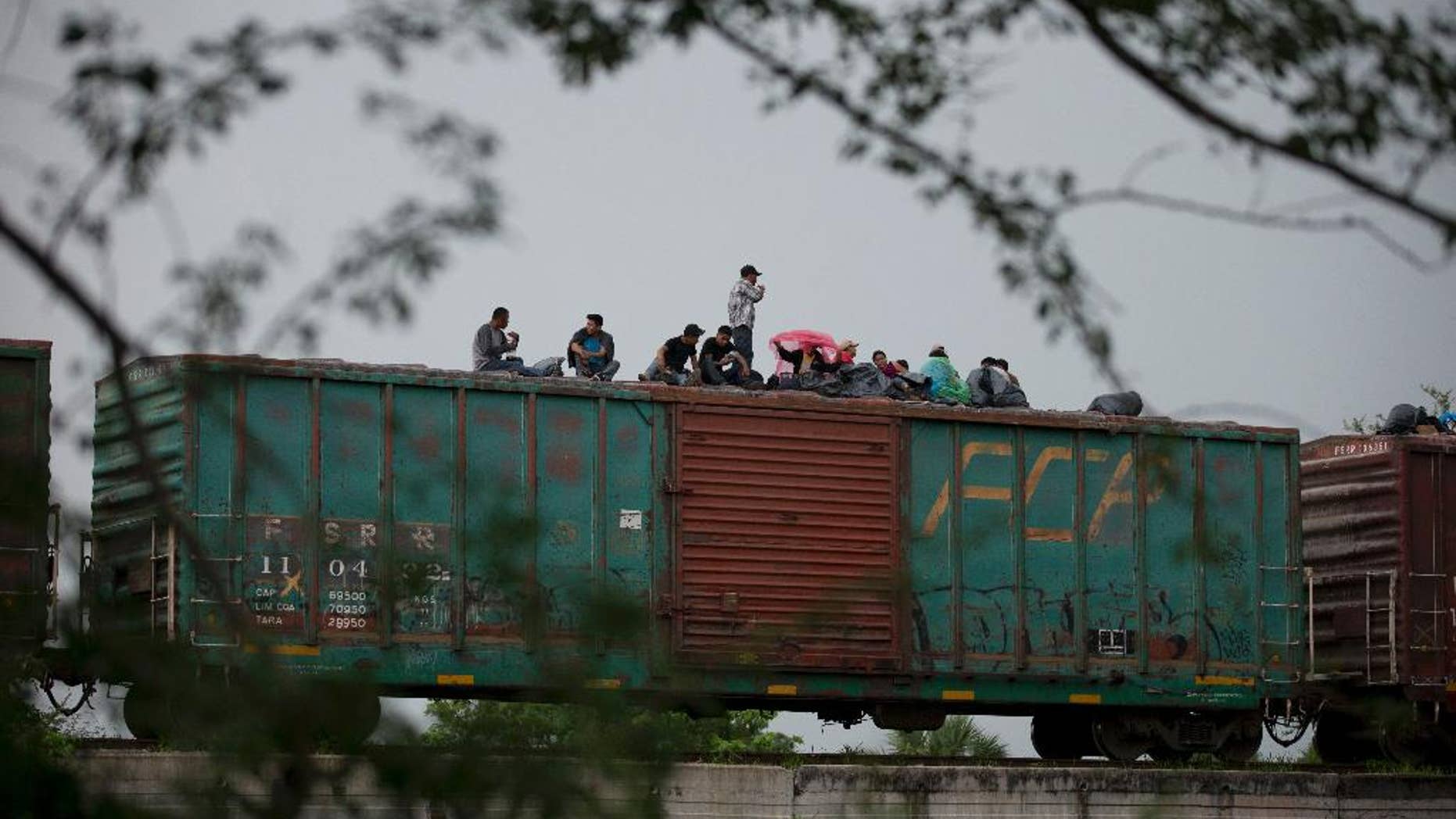 FILE - In this June 20, 2014 file photo, Central American migrants wait atop the freight train they had been traveling north on, as it starts to rain after the train suffered a minor derailment outside Reforma de Pineda, Chiapas state, Mexico. Mexico now deports more Central American migrants than the United States, a dramatic shift since the U.S. asked Mexico for help a year ago with a spike in illegal migration, especially among unaccompanied minors. (AP Photo/Rebecca Blackwell, File)