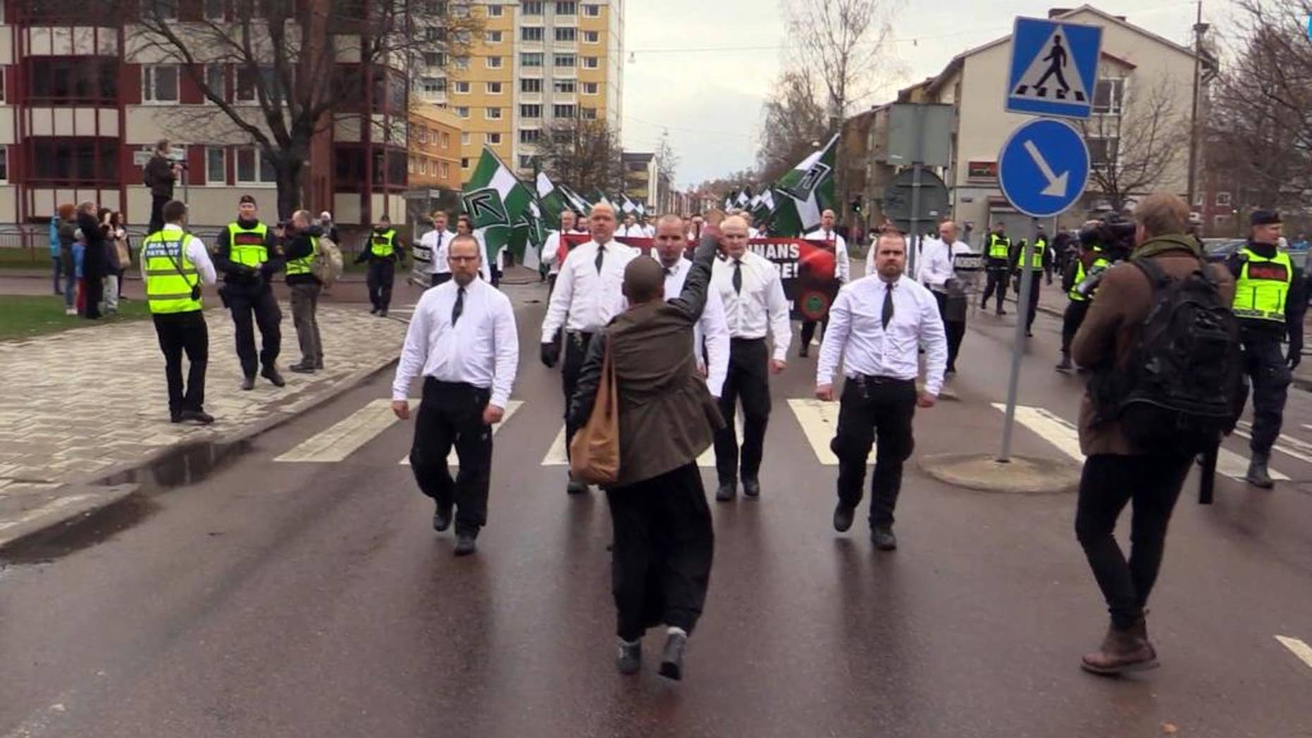 In this image made from video from Sunday, May 1, 2016, Tess Asplund gestures towards a group of far-right protesters in Borlange, Sweden. A black woman who stood up to 300 neo-Nazis in Sweden hopes her gesture will draw attention to the fight against racism in the Scandinavian country. Tess Asplund tried to block the path of the Nordic Resistance Movement as the right-wing extremist group marched in the town of Borlange on May 1. An image of Asplund facing the neo-Nazis up close with a clenched fist has been shared thousands of times on social media in Sweden and internationally. (DT.se via AP) SWEDEN OUT