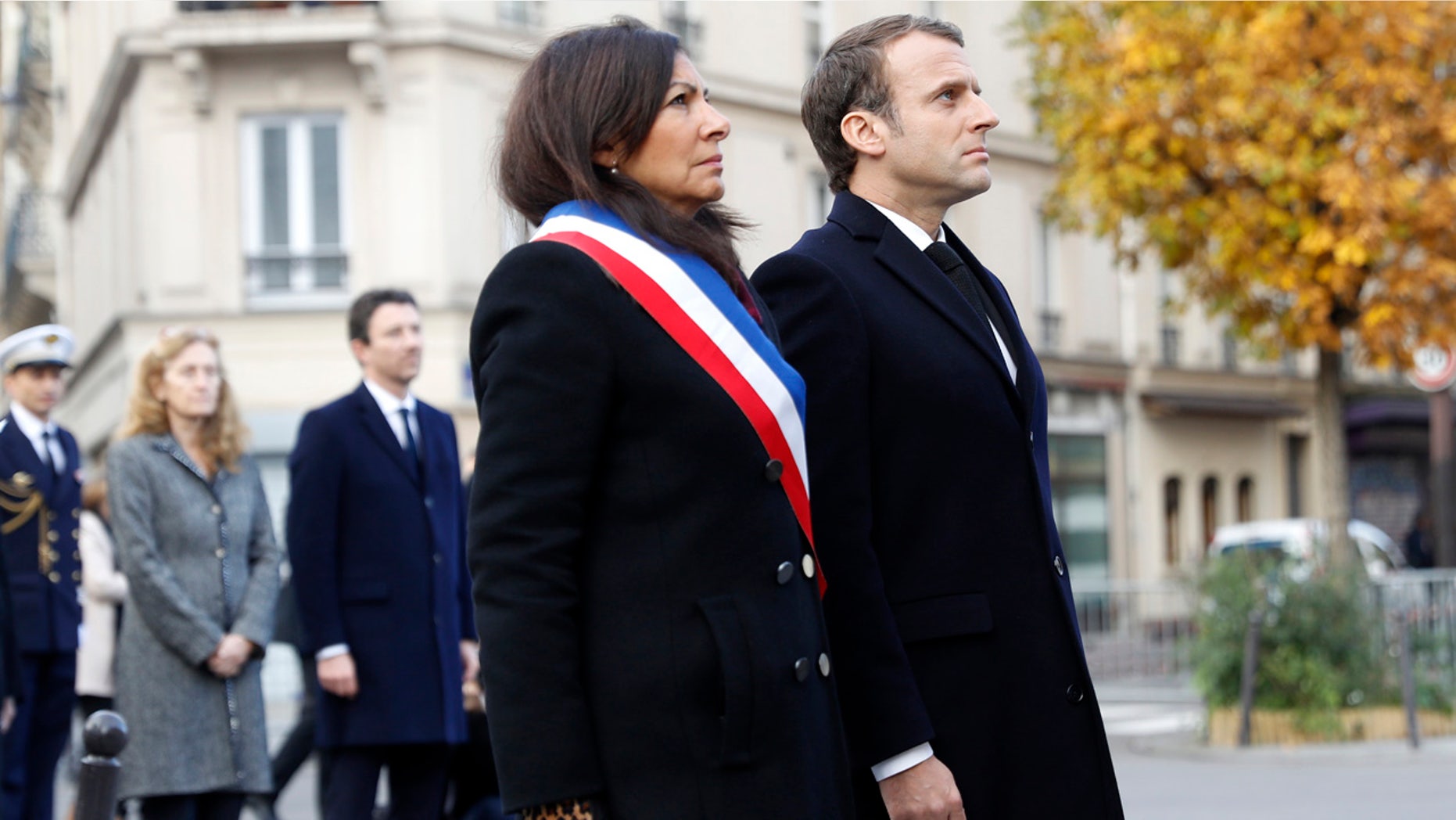 French President Emmanuel Macron and Paris mayor Anne Hidalgo, left, stand in front of a commemorative plaque facing the 'Le Carillon' bar and 'Le Petit Cambodge' restaurant during a ceremony marking the second anniversary of the Paris attacks, Monday Nov.13 2017