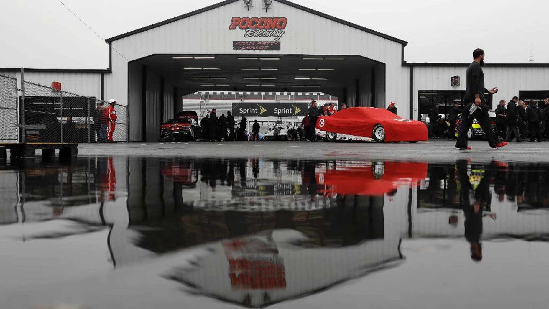 Crew members push the car of Kyle Larson in the garage area before the NASCAR Sprint Cup series auto race, Sunday, June 5, 2016, in Long Pond, Pa. (AP Photo/Matt Slocum)