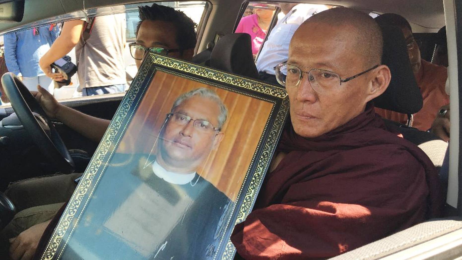 FILE - In this Monday, Jan. 30, 2017, file photo, a Buddhist monk holds a portrait of Ko Ni, legal adviser and prominent member of Myanmar's Muslim minority, during his funeral in Yangon, Myanmar. Myanmar police say a conspirator identified as Myint Swe behind the assassination of Ko Ni, a longtime legal adviser of the ruling party National League for Democracy and leader Aung San Suu Kyi, has been arrested and under interrogation since Monday. (AP Photo/Esther Htusan)
