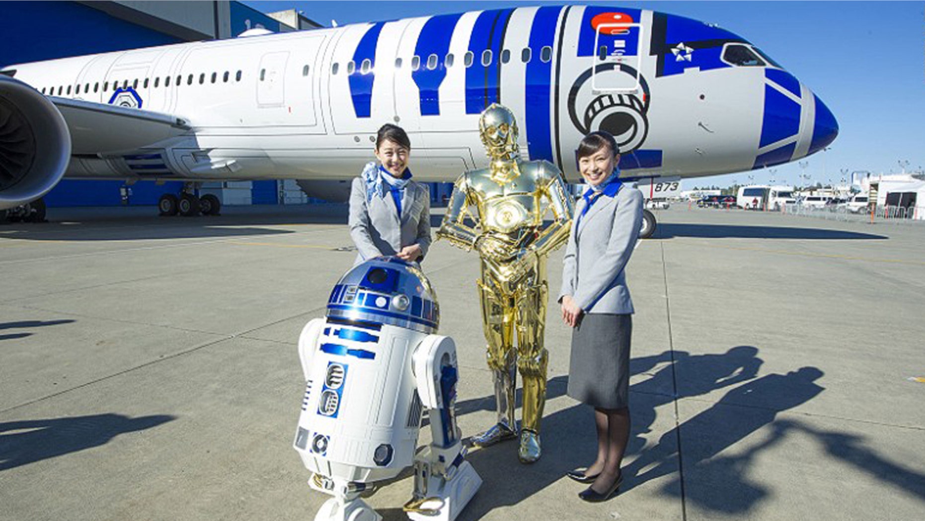 Flight attendants pose in front of the aircraft with R2-D2 and C-3PO from "Star Wars."