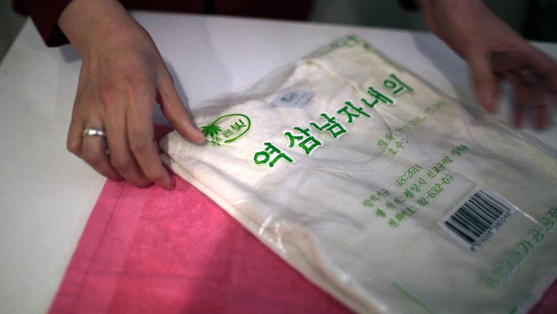 A saleswoman shows off a locally produced t-shirt and towel made out of hemp in Pyongyang. Hemp is, in fact, grown in North Korea with official sanction.