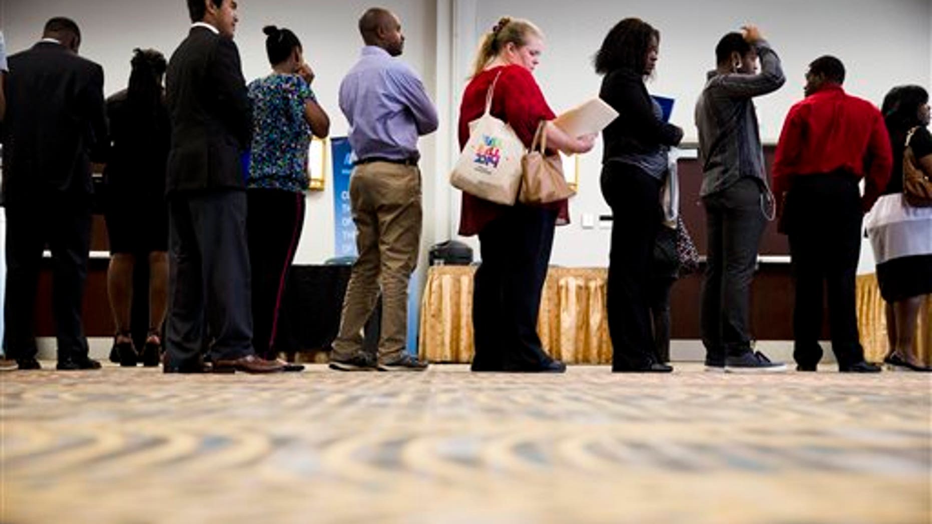 In this June 23, 2014 photo, job seekers wait in line to meet with recruiters during a job fair in Philadelphia. The government issues the July jobs report on Friday, Aug. 1, 2014.