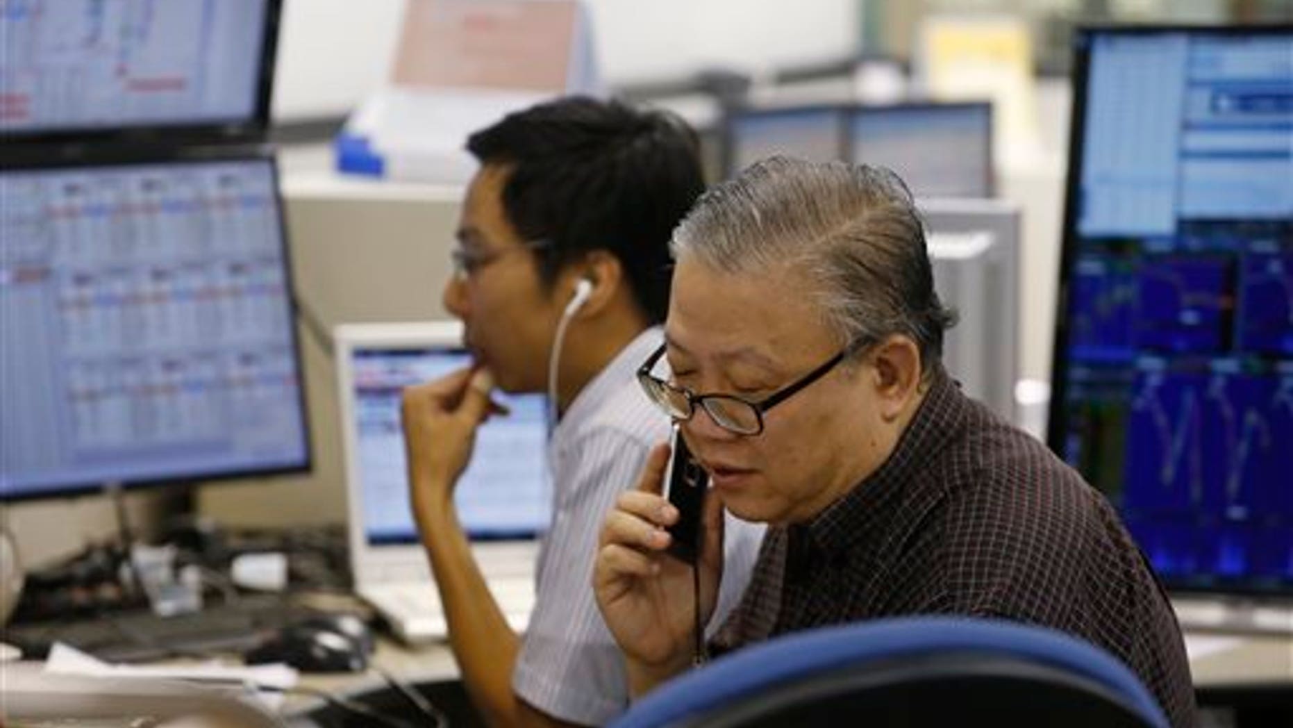 A broker talks on phone at a brokerage firm in Hong Kong, Wednesday, July 8, 2015.