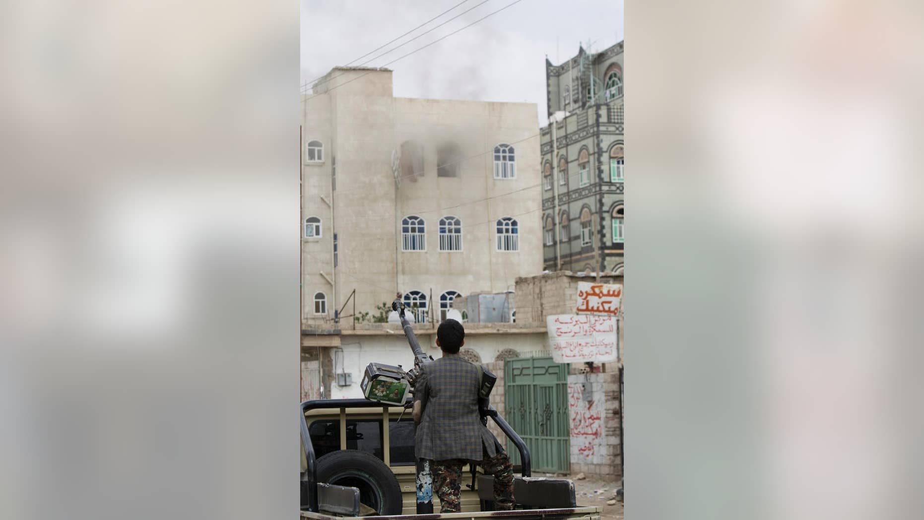 A Shiite fighter known as a Houthi holds a weapon as he looks at smoke rising from a building after a Saudi-led airstrike on a street in Sanaa, Yemen, Wednesday, April 8, 2015. Iran dispatched a naval destroyer and another vessel Wednesday to waters near Yemen as the United States quickened weapons supply to the Saudi-led coalition striking rebels there, underlining how foreign powers are deepening their involvement in the conflict. (AP Photo/Hani Mohammed)
