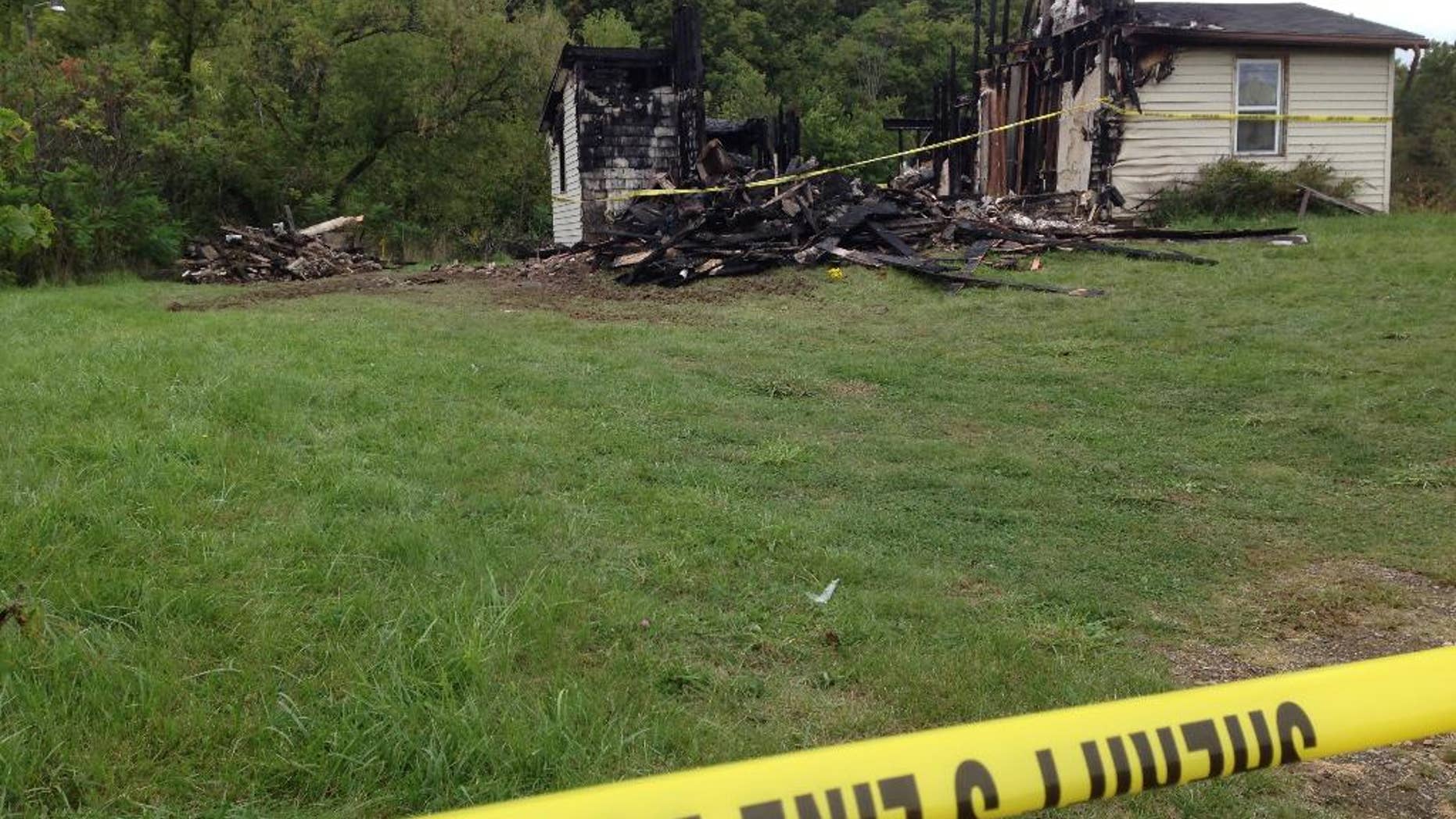 Police tape cordons off the remains of a house. Wednesday, Sept. 14, 2016, in rural Richland County, near Mansfield, Ohio, where authorities say a woman's body was found nearby. Police say a suspect in the abduction of a woman in neighboring Ashland on Tuesday confessed to killing a woman in the house in June, which was then destroyed in a fire. (AP Photo/Ann Sanner)