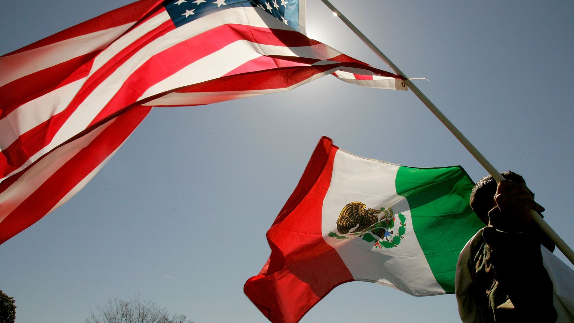 WASHINGTON - MARCH 27: A protester holds an American flag and a Mexican flag while participating in a protest on the west front of the U.S. Capitol March 27, 2006 in Washington, DC. Thousands of immigration advocates rallied on Capitol Hill to protest the immigration bill that is before Congress. (Photo by Mark Wilson/Getty Images)