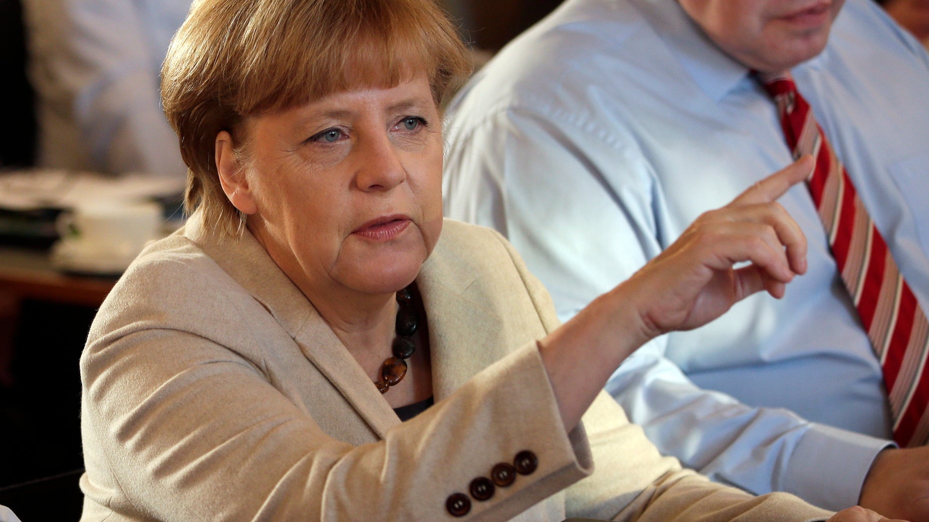 German Chancellor Angela Merkel, left, points as she and Peter Altmaier, Head of the Federal Chancellery, right, attend a cabinet meeting as part of a two day closed meeting of the German government at the Meseberg palace near Berlin, Germany, Thursday, Jan. 23, 2014. (AP Photo/Michael Sohn)