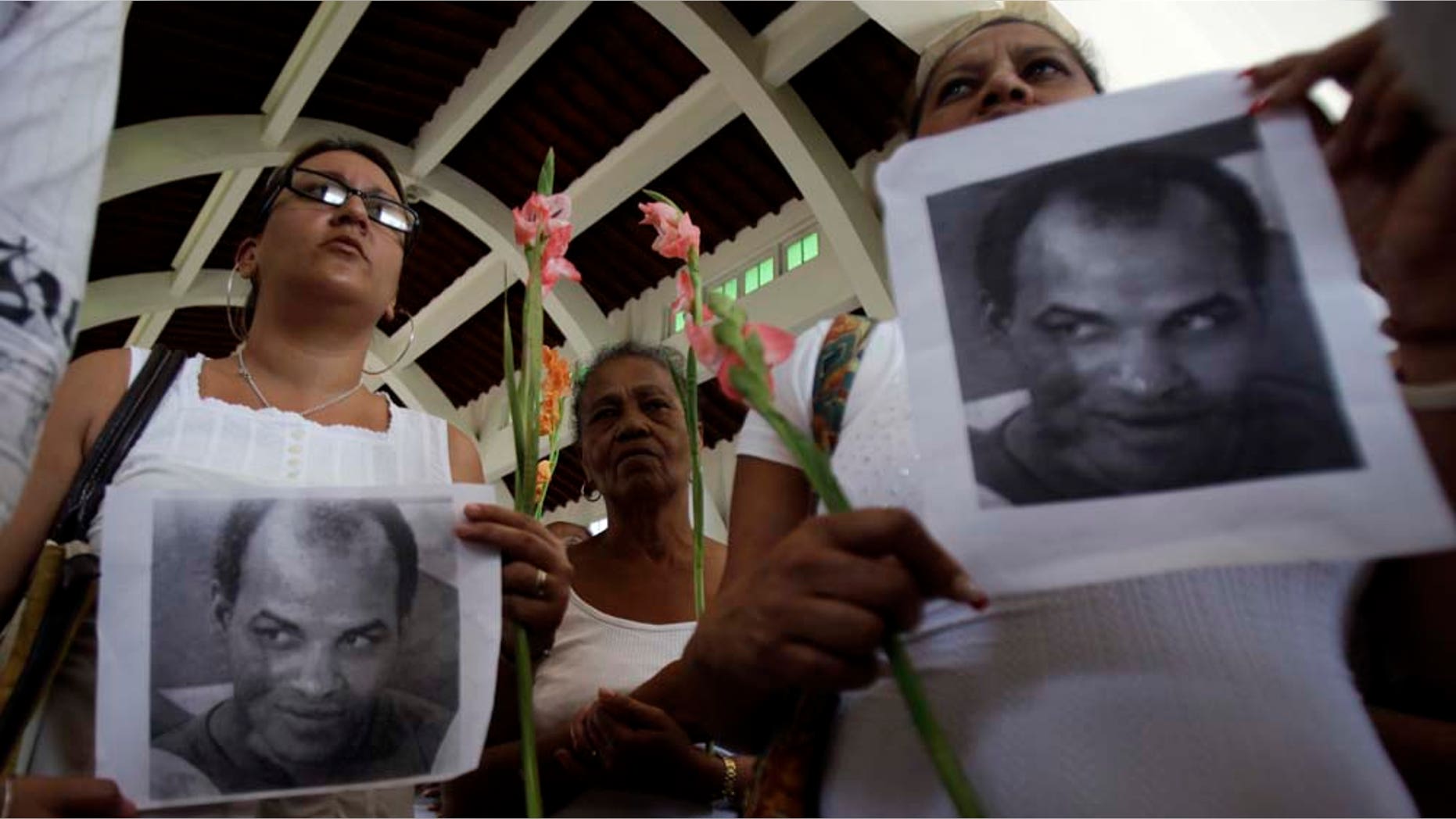 Members of Cuba's dissident group Ladies in White hold up photographs of the late political prisoner Orlando Zapata Tamayo during their weekly march in Havana, Cuba, Sunday, Feb. 6, 2011. Tamayo died on Feb. 23 following a lengthy hunger strike. Cuba freed Guido Sigler , a prominent political prisoner, on Friday and the Roman Catholic Church said Angel Moya, another political prisoner, would be released soon and allowed to stay in the country. (AP Photo/Javier Galeano)