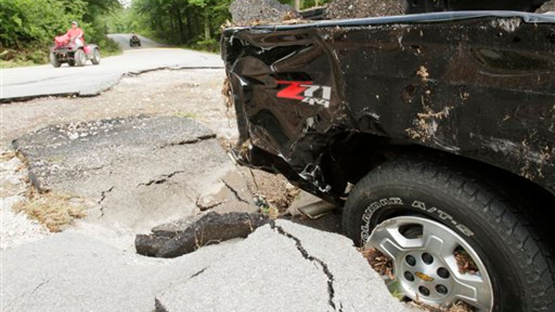 June 23: In this file photo sblah blah blagh earch and rescue workers ride all terrain vehicles past a truck that was damaged by flood waters at Albert Pike campground near Caddo Gap, Ark.