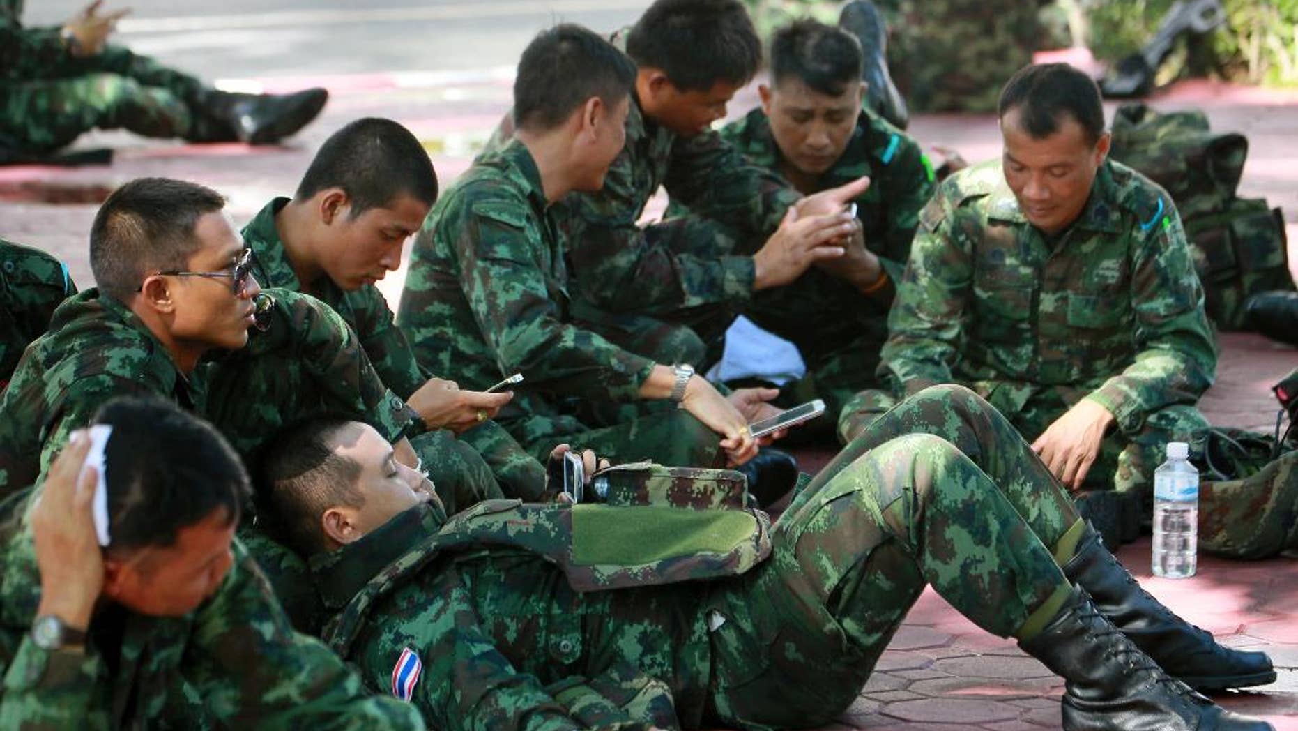 Thai soldiers rest on the ground at police headquarters after being deployed to prevent an anti-coup demonstration in Bangkok, Thailand Sunday, June 1, 2014. An anti-coup activist in Thailand called Friday for a weekend rally to defy the military government's ban on demonstrations, urging those opposed to the takeover to wear masks and be ready for cat-and-mouse chases with soldiers in the capital. (AP Photo/Wason Wanichakorn)