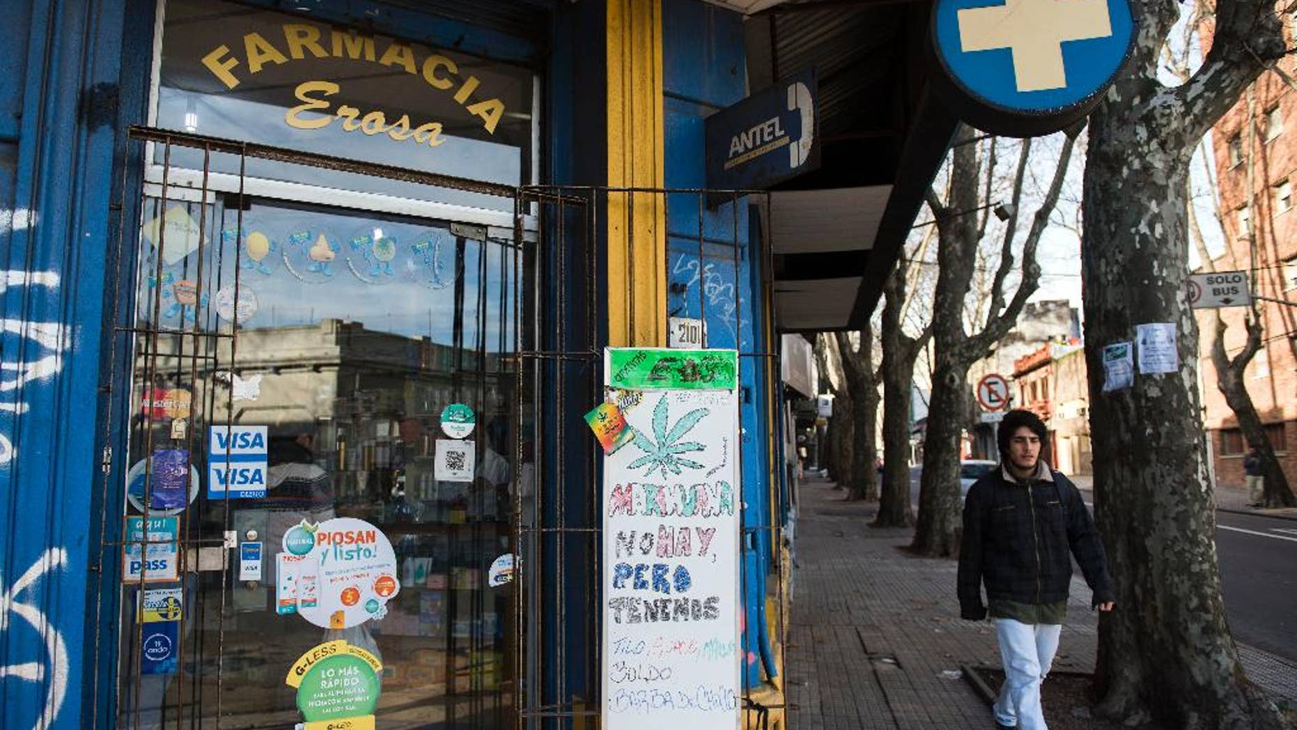 FILE - In this June 28, 2016 file photo, the Erosa pharmacy displays a sign at the front door telling clients that they do not have marijuana for sale, but they sell other herbs known for their medical effects, in downtown Montevideo, Uruguay. Uruguay is beginning to register people who want to legally buy marijuana at pharmacies as part of the world's first government-regulated national marketplace for pot. Authorities announced the registry's launch Tuesday, May 2, 2017. (AP Photo/Matilde Campodonico, File)