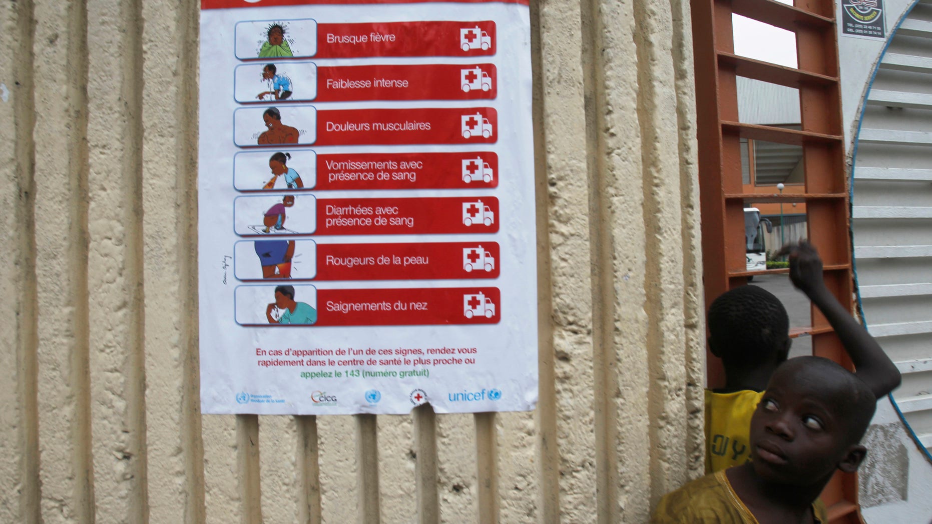 Boys stand next to a poster, pertaining to the Ebola virus, during a training session by Sierra Leone's national soccer team at the Felix Houphouet Boigny stadium in Abidjan, September 5, 2014. Ivory Coast will host their African Nations Cup qualifier against Ebola-affected Sierra Leone this weekend following a special meeting of the country?s national security council. The decision, announced in a government statement published in local media on Tuesday, comes one week after the government said it would not allow the match to go ahead, citing concerns over a possible Ebola outbreak. REUTERS/Luc Gnago (IVORY COAST - Tags: SPORT SOCCER HEALTH) - RTR4552S