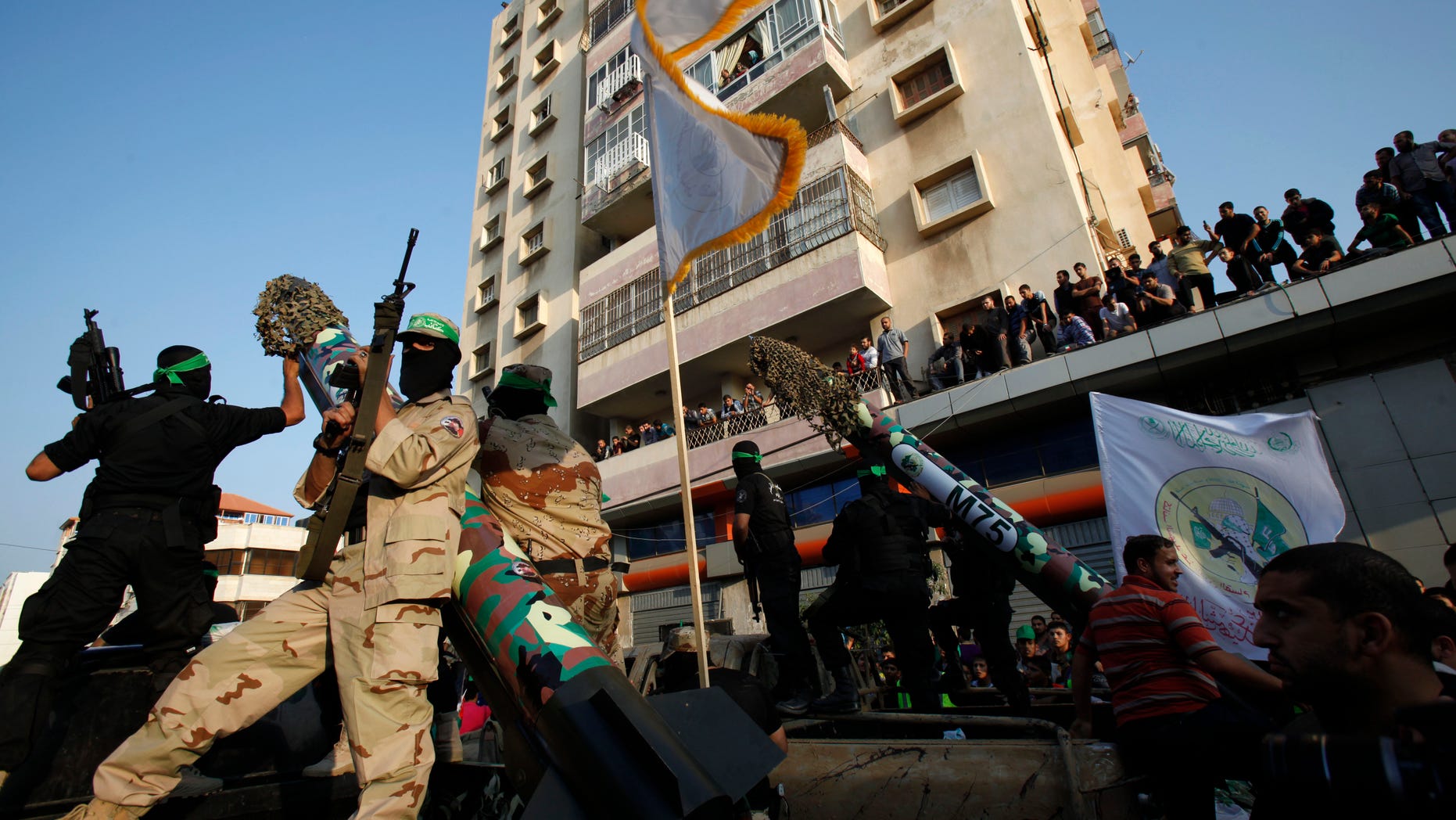 Masked Palestinian members of the Ezz Al-Din Al Qassam brigade, the military wing of Hamas, stand behind mock rockets on trucks during a parade to mark the anniversary of a battle against Israel in Gaza City.