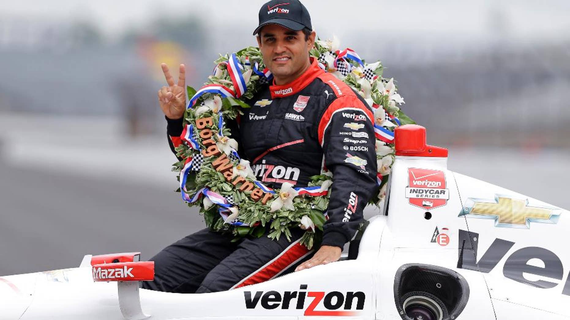 Juan Pablo Montoya, of Colombia, poses in his car during the traditional winners photo session at Indianapolis Motor Speedway in Indianapolis, Monday, May 25, 2015. Montoya won the 99th running of the Indianapolis 500 auto race on Sunday. (AP Photo/Michael Conroy)