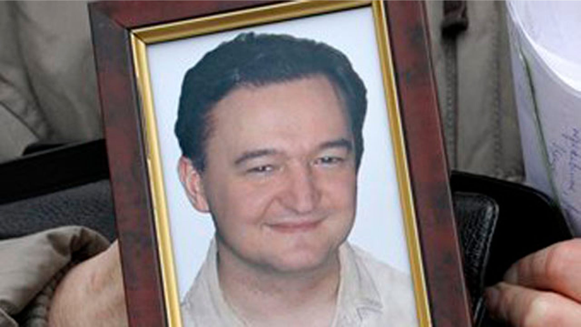 This is a Monday, Nov. 30, 2009 file photo showing a portrait of lawyer Sergei Magnitsky who died in jail, as it is held by his mother Nataliya Magnitskaya, as she speaks during an exclusive interview with the AP in Moscow, Russia, Monday, Nov. 30, 2009.