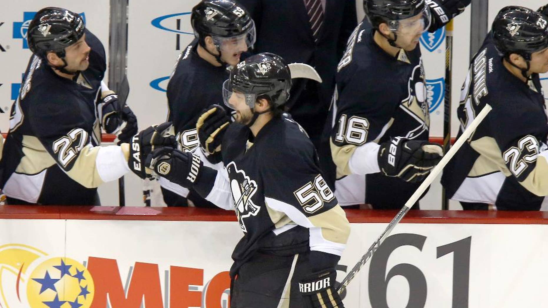 Pittsburgh Penguins Kris Letang (58) is greeted by teammates on the bench after scoring in the first period of an NHL hockey game against the Carolina Hurricanes, Friday, Nov. 28, 2014, in Pittsburgh. (AP Photo/Keith Srakocic)