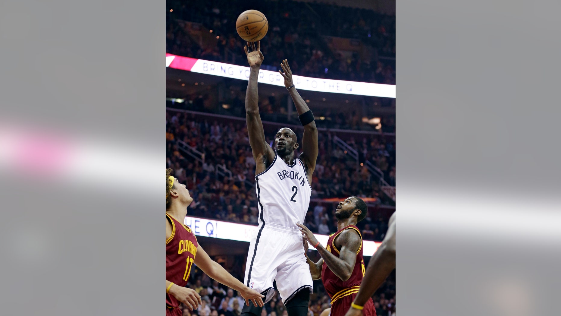 Brooklyn Nets' Kevin Garnett , center, shoots over Cleveland Cavaliers' Anderson Varejao, left, of Brazil, and Earl Clark during the first quarter of an NBA basketball game Wednesday, Oct. 30, 2013, in Cleveland. (AP Photo/Tony Dejak)