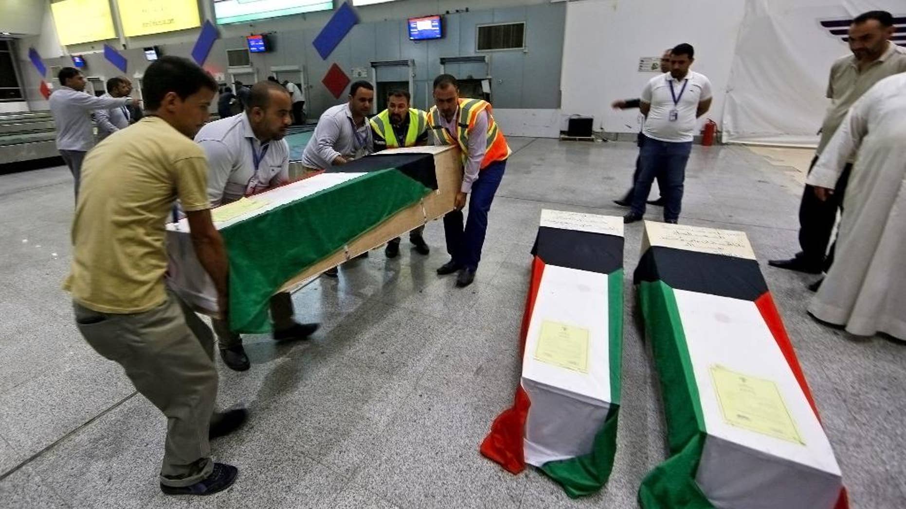 In this Saturday, June 27, 2015 photo, men arrange coffins draped with Kuwaiti flags belonging to a victim of a suicide bombing that targeted a Shiite mosque in Kuwait on Friday, as they arrive to Najaf Airport, for the funeral procession, in the Shiite holy city of Najaf, Iraq. Kuwaiti authorities on Sunday identified the suicide bomber behind an attack on a Shiite mosque that killed more than two dozens as a Saudi citizen who flew into the Gulf nation just hours before he blew himself up. (AP Photo/ Jaber al-Helo)