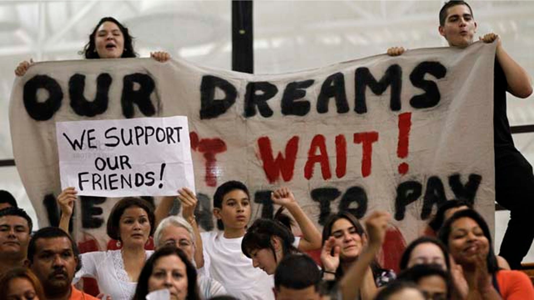 FILE - In this Sept. 26, 2011 photo, college student Jasmine Oliver, of Warwick, R.I., top left, and Javier Gonzalez, of Pawtucket, R.I., top right, display a banner and shout their support for allowing illegal immigrants to pay in-state tuition rates while attending public colleges in the state, during a Board of Governors of Higher Education meeting on the campus of the Community College of Rhode Island, in Warwick, R.I. But research varies on the effects of resident tuition rates for illegal immigrants, including on enrollment, and students may still face a tough road even if they graduate with a college degree: Without passage of the DREAM Act or other federal immigration reform, illegal immigrant students have no pathway to legal status, and it remains illegal for employers to hire them. (AP Photo/Steven Senne, File)