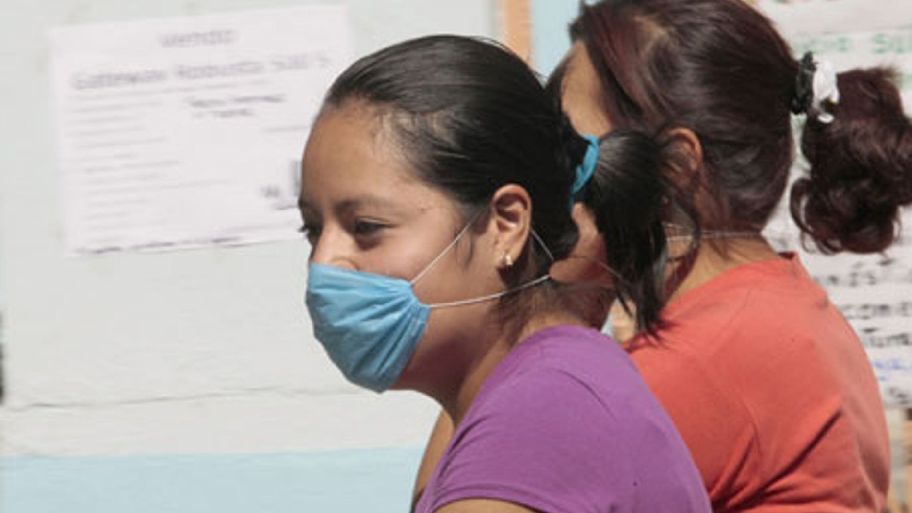 April 24, 2009: Women wear masks as they walk past a closed school in Mexico City.
