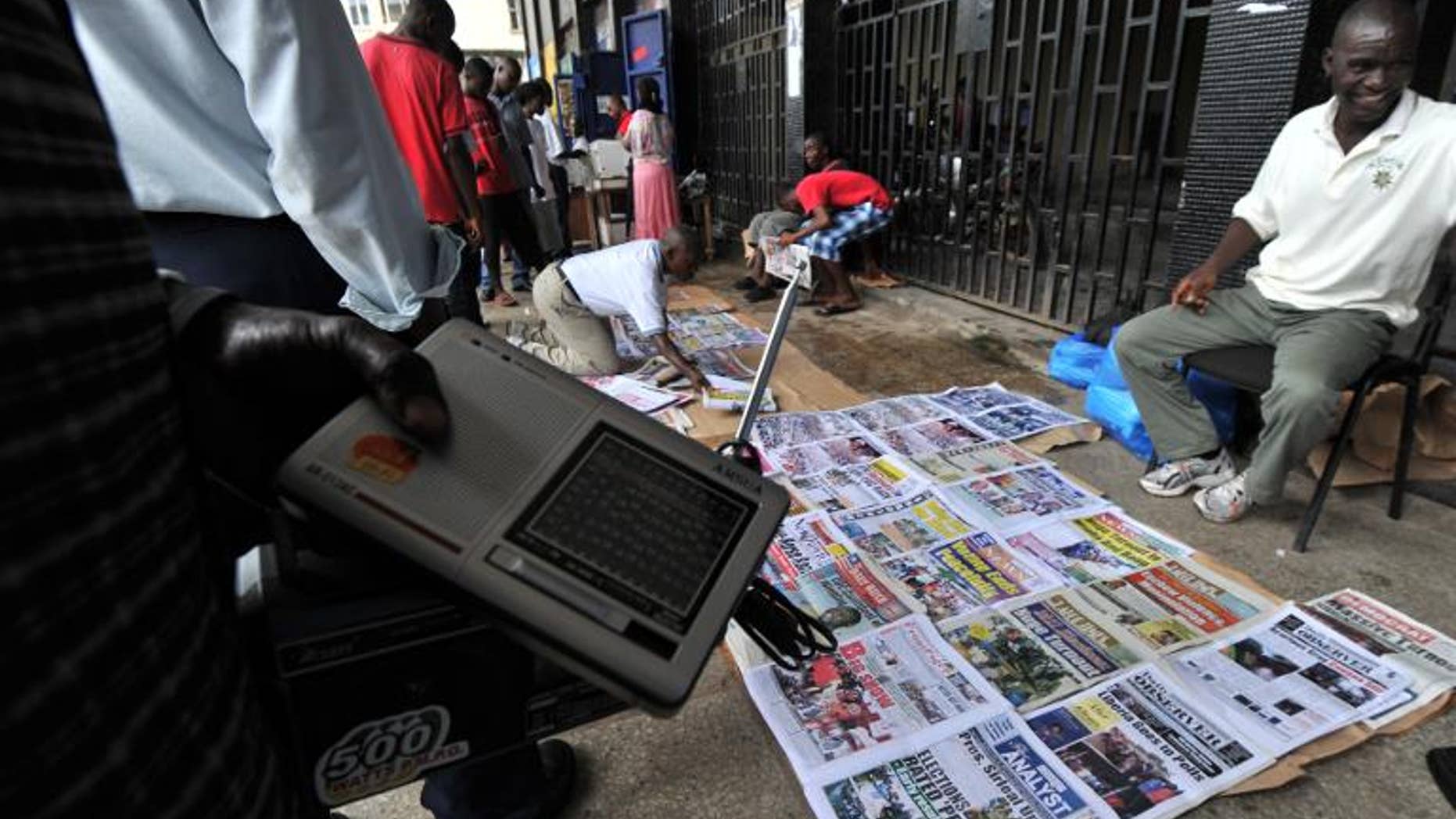 People look at newspaper headlines on a street in Monrovia on October 12, 2011